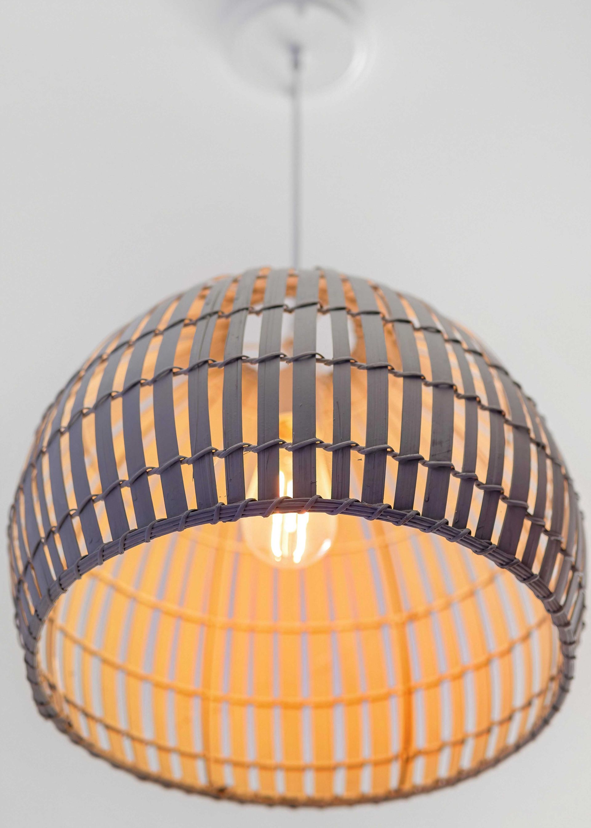 Hanging dome pendant lamp with black and orange woven slats, glowing warm light inside