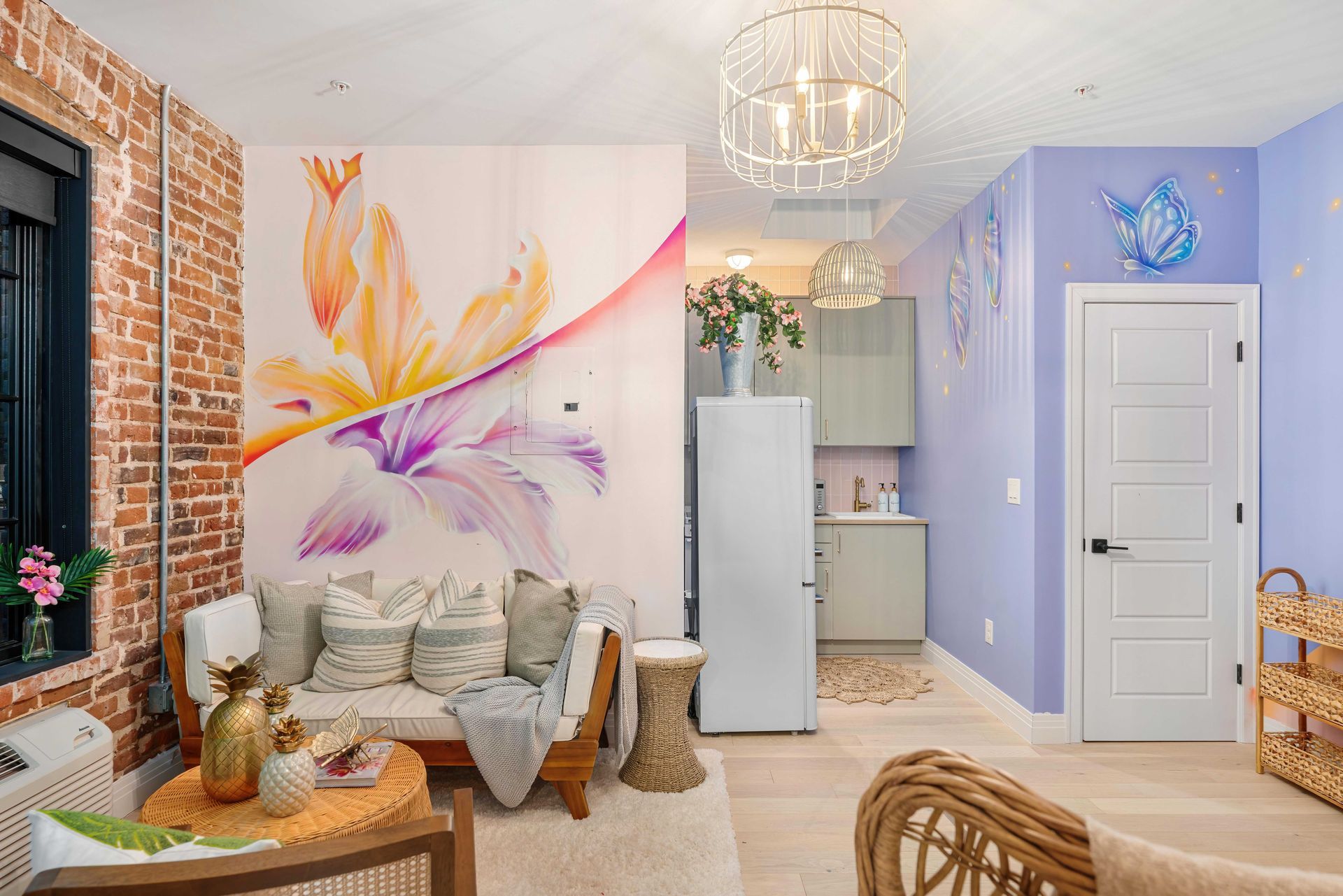 Colorful living room with mural, brick wall, white sofa, chandelier, and lavender entryway