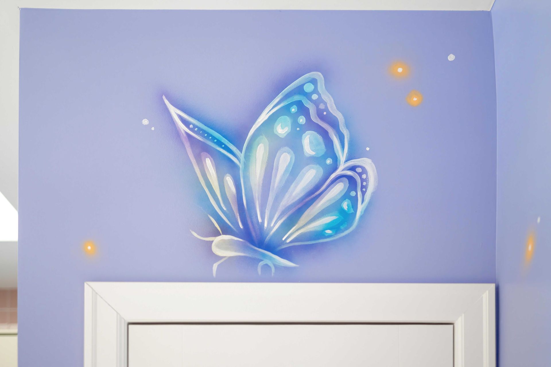 Blue butterfly wall decal above a white door frame on a lavender wall