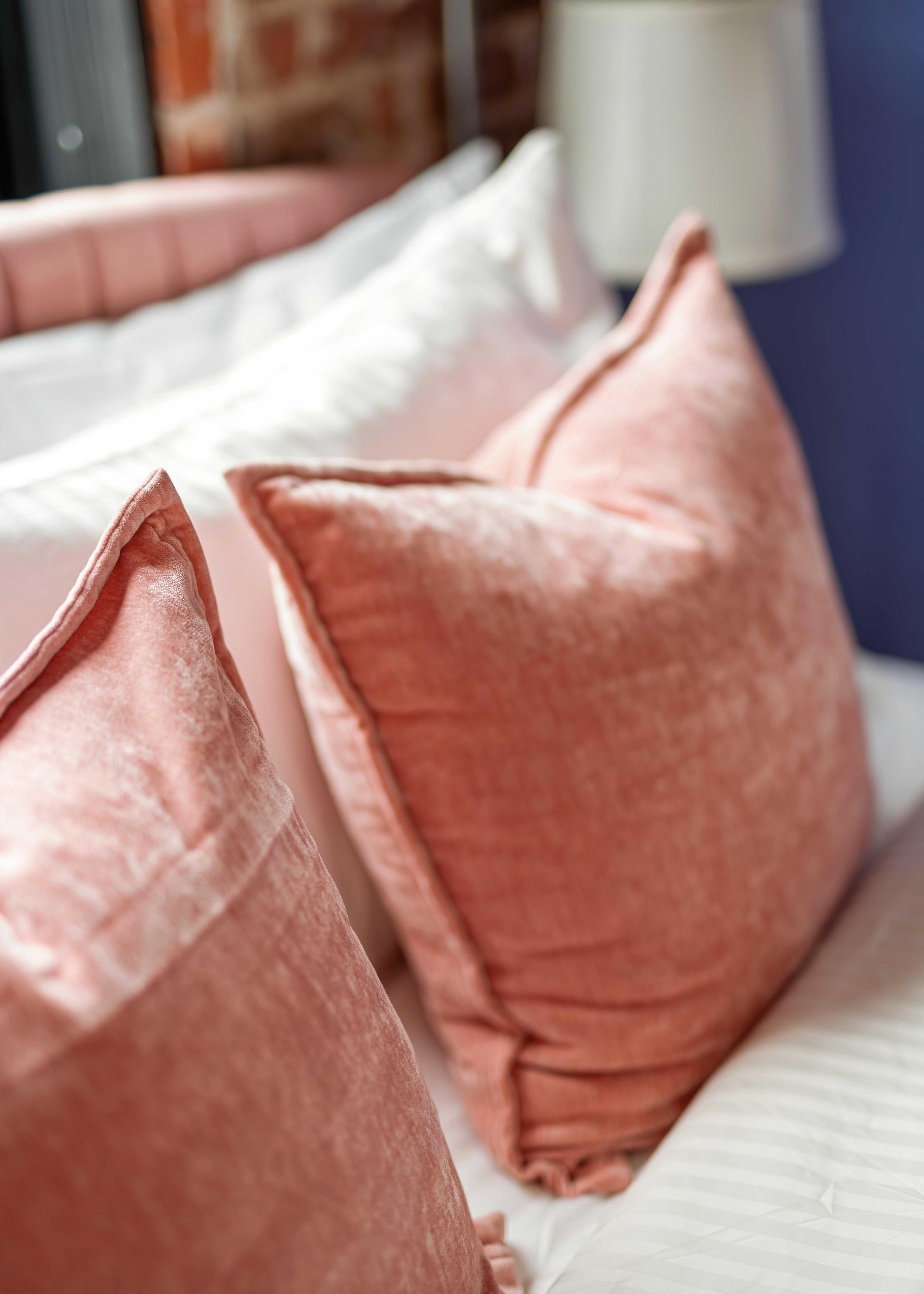 Pink throw pillows on a white bed with a tufted headboard and soft bedding.