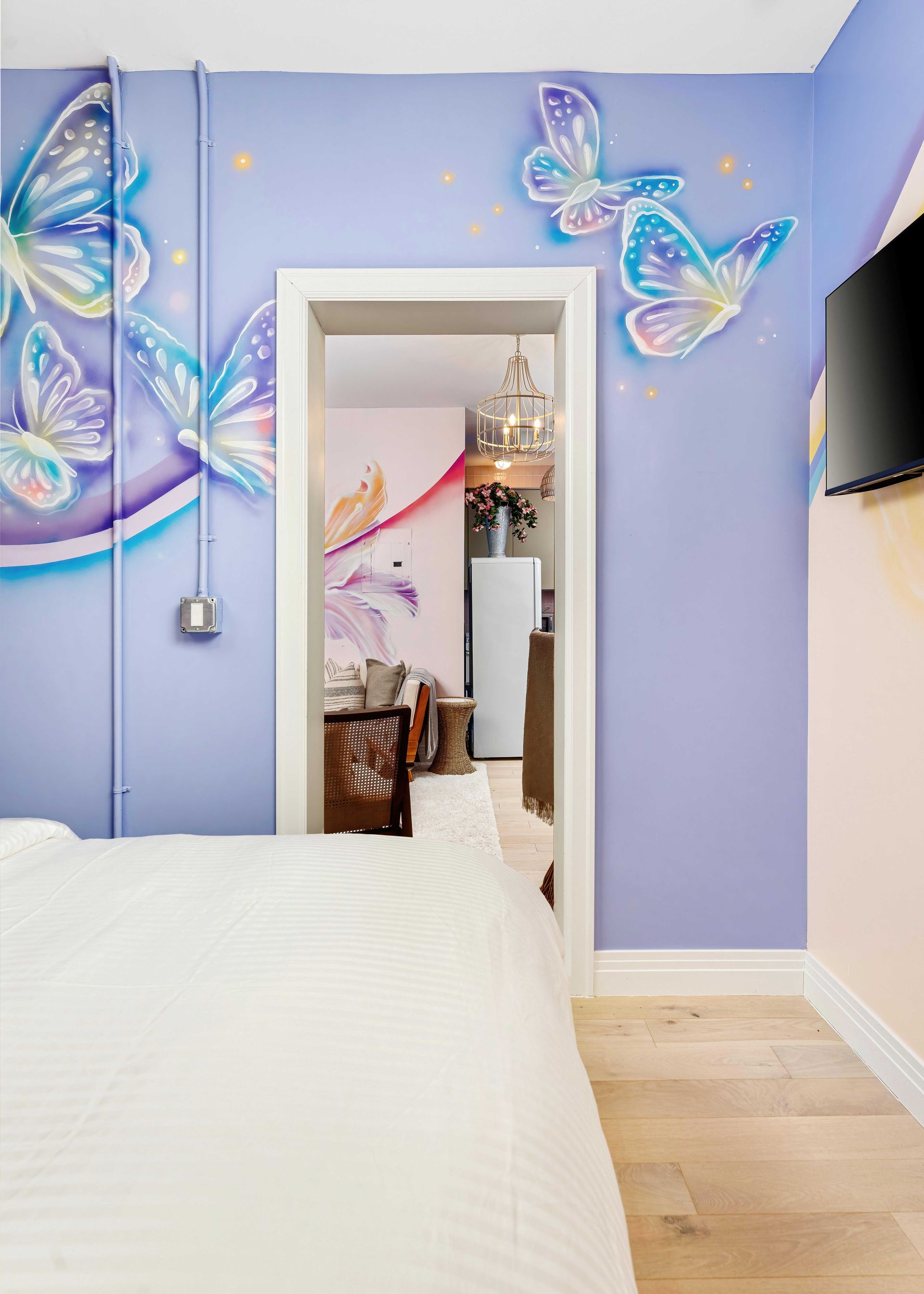 Butterfly-themed lavender bedroom with bed, wall decor, and open doorway to a hallway