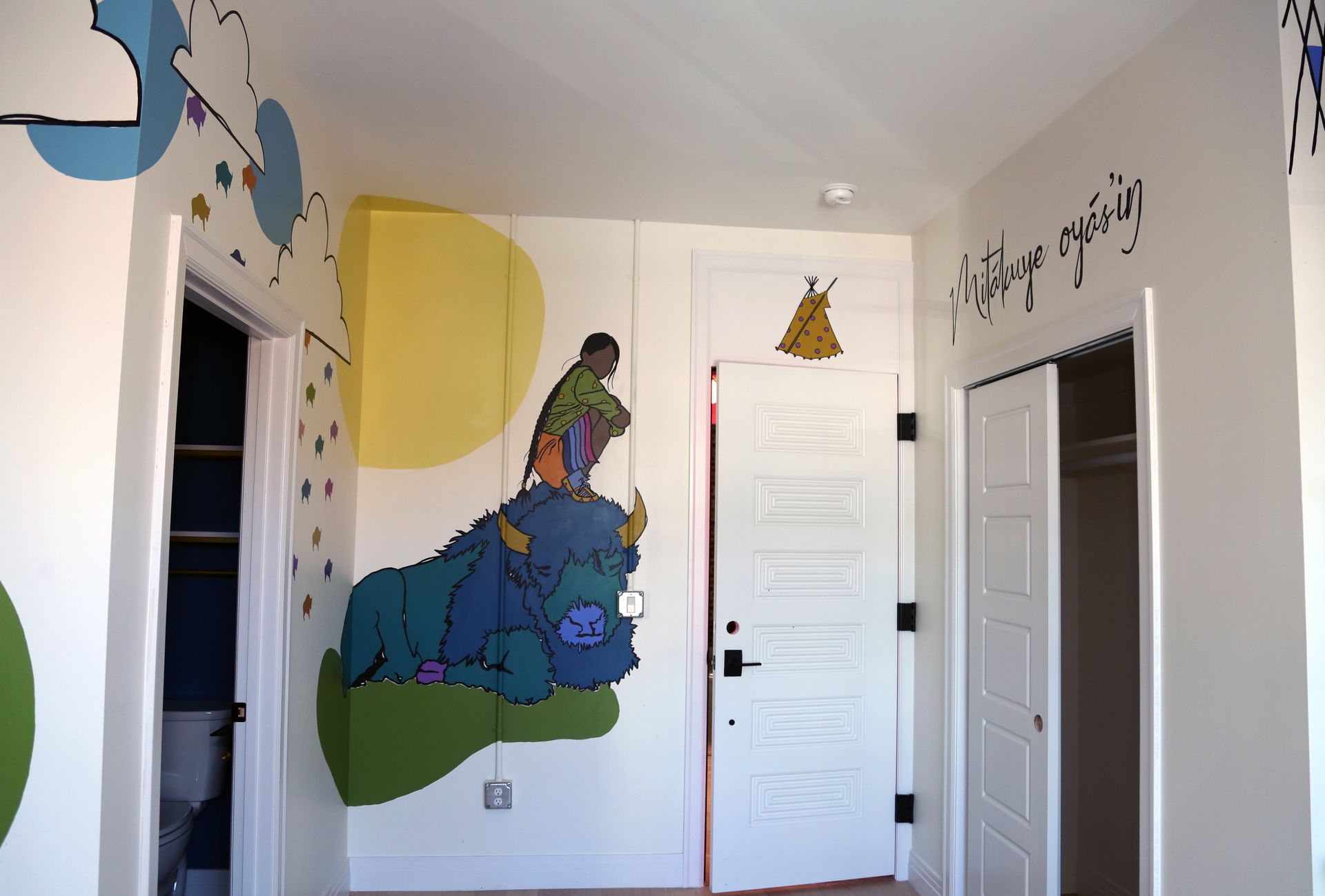 Colorful hallway wall mural with cartoon animals, white doors, and decorative wall lettering