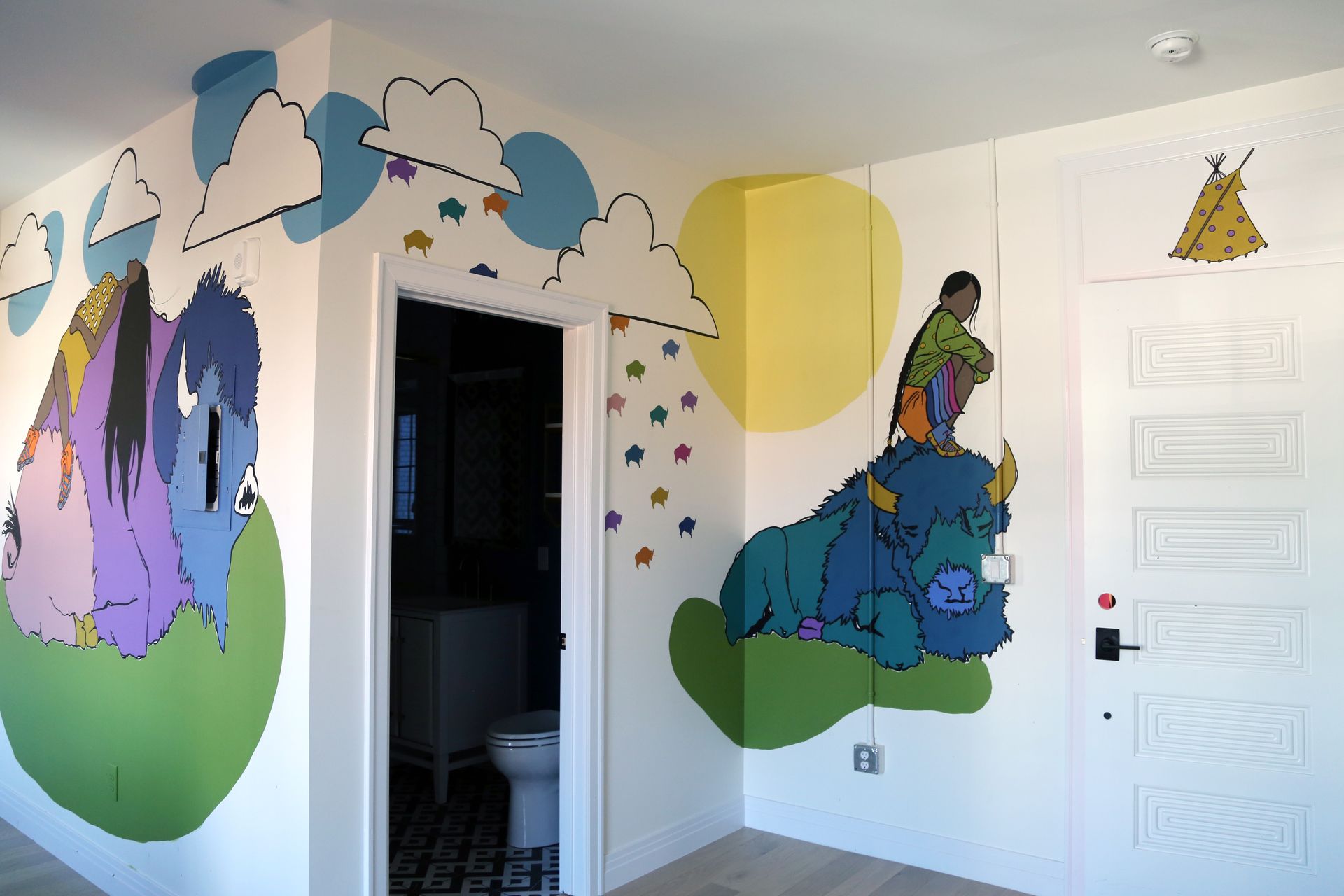 Colorful children's mural in a hallway with a white door and an open bathroom doorway
