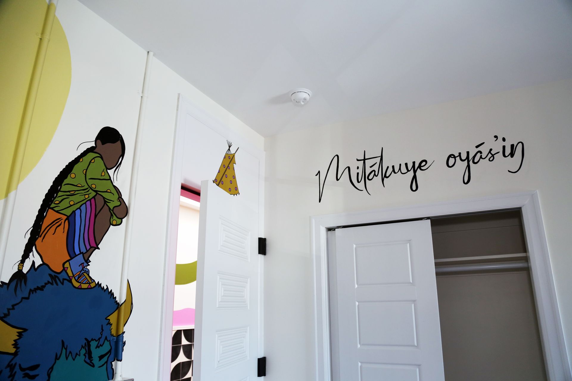 Colorful mural and Turkish wall quote above a white doorway in a bright room