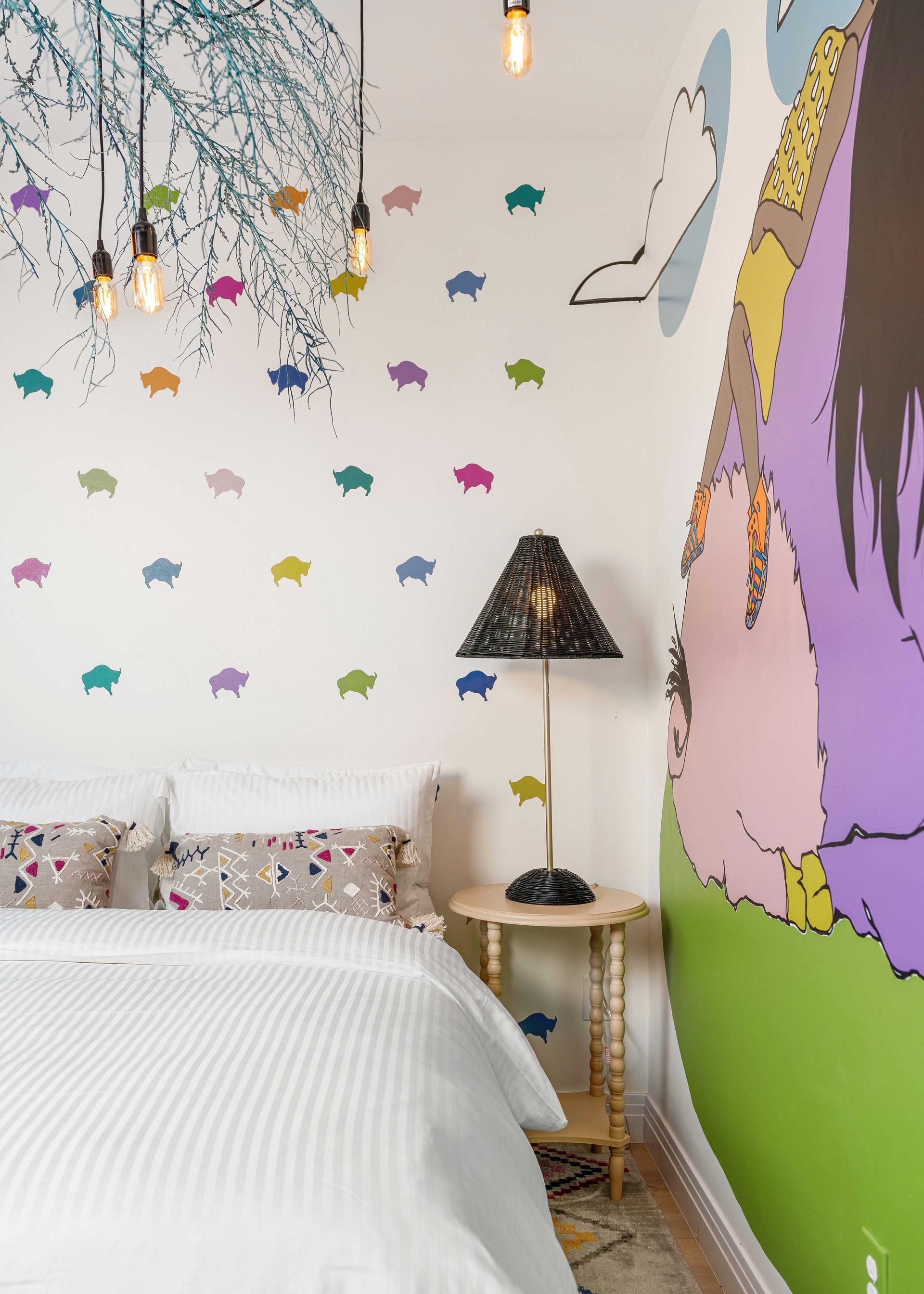 Colorful bedroom with white bed, star wall decals, bedside lamp, and large unicorn mural