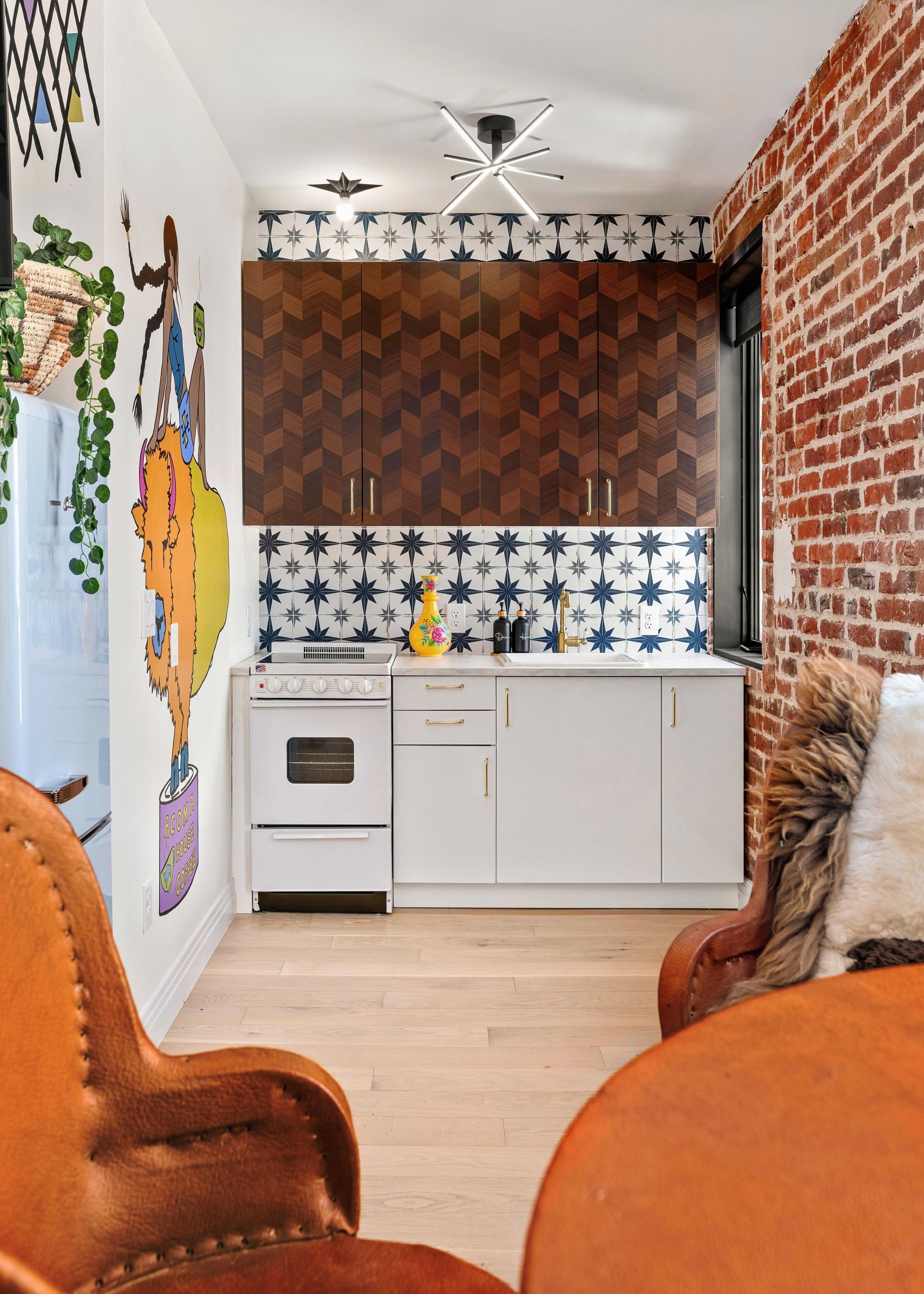 Cozy kitchen nook with brick wall, patterned backsplash, white cabinets, and warm leather chairs
