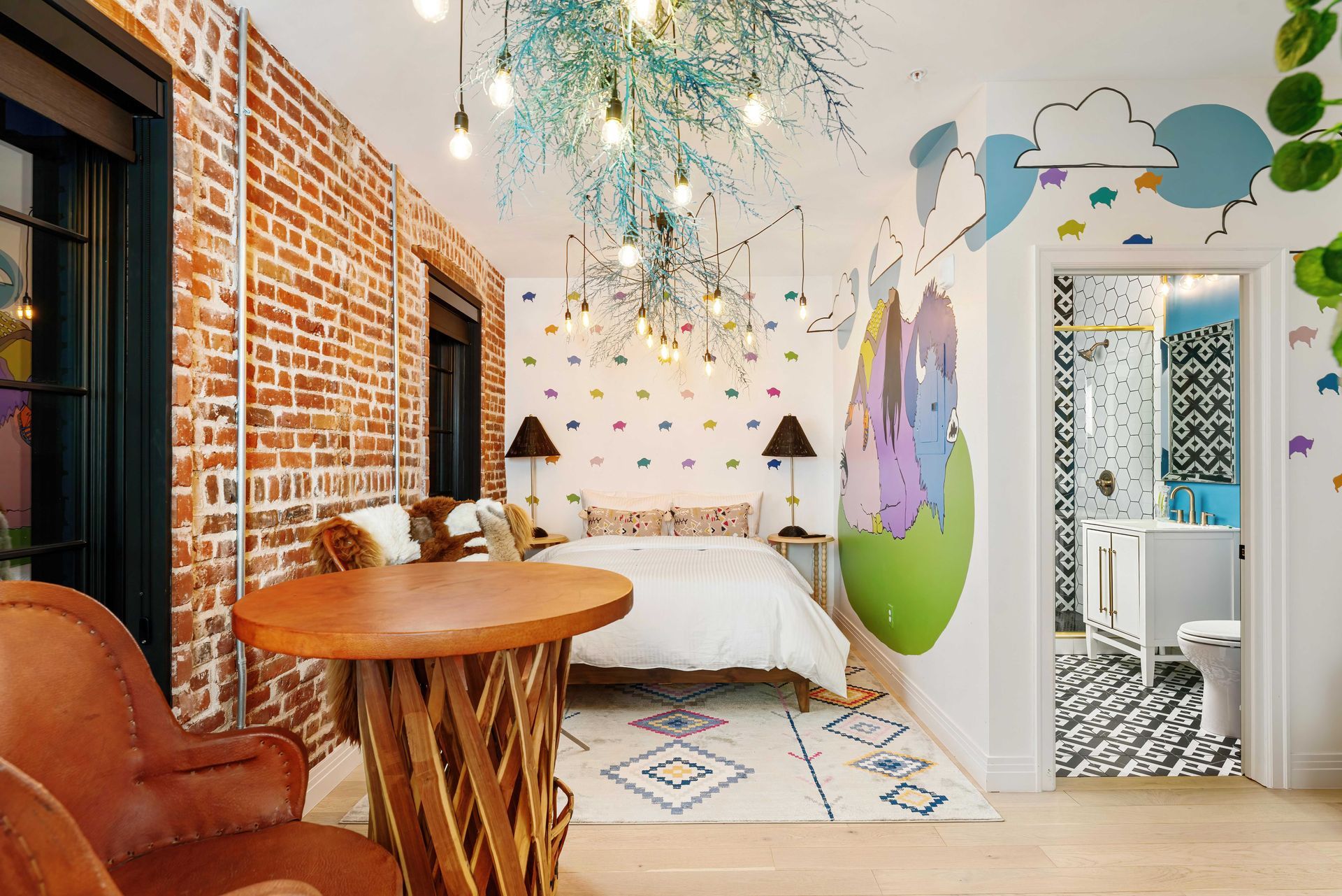 Cozy studio bedroom with exposed brick, wood table, bed, and colorful wall mural