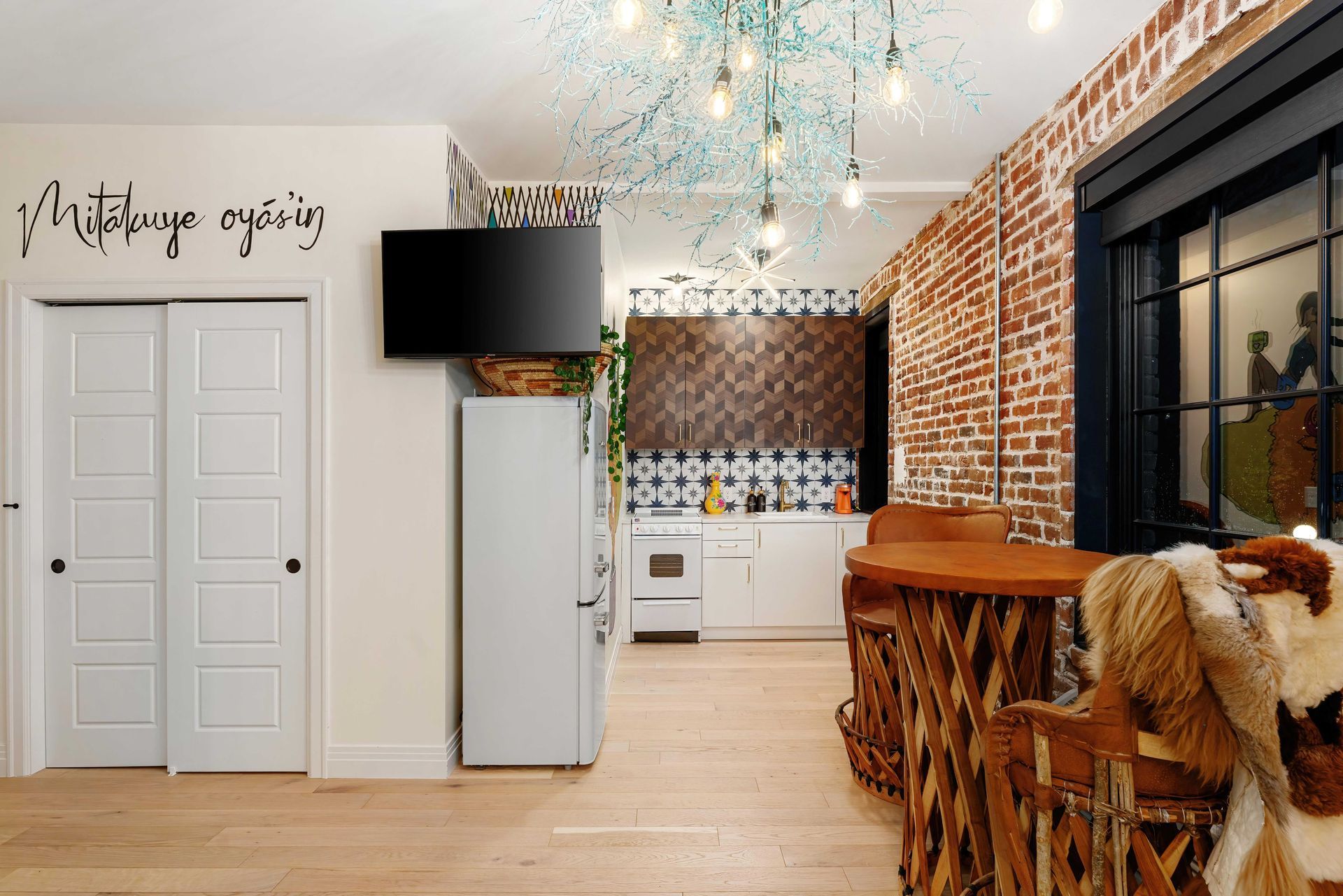 Stylish kitchen with brick wall, white cabinets, hanging lights, and a rustic wooden island