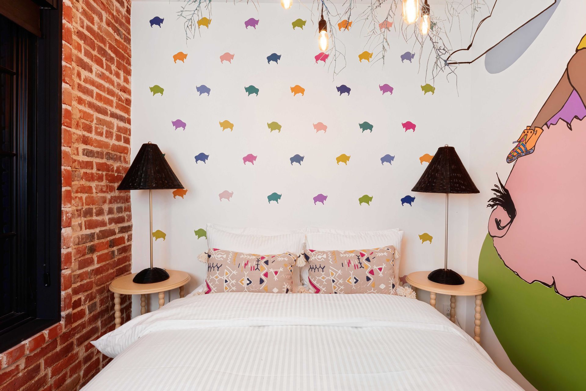 Small bedroom with a white bed, patterned pillows, brick wall, and colorful animal decals on the wall.