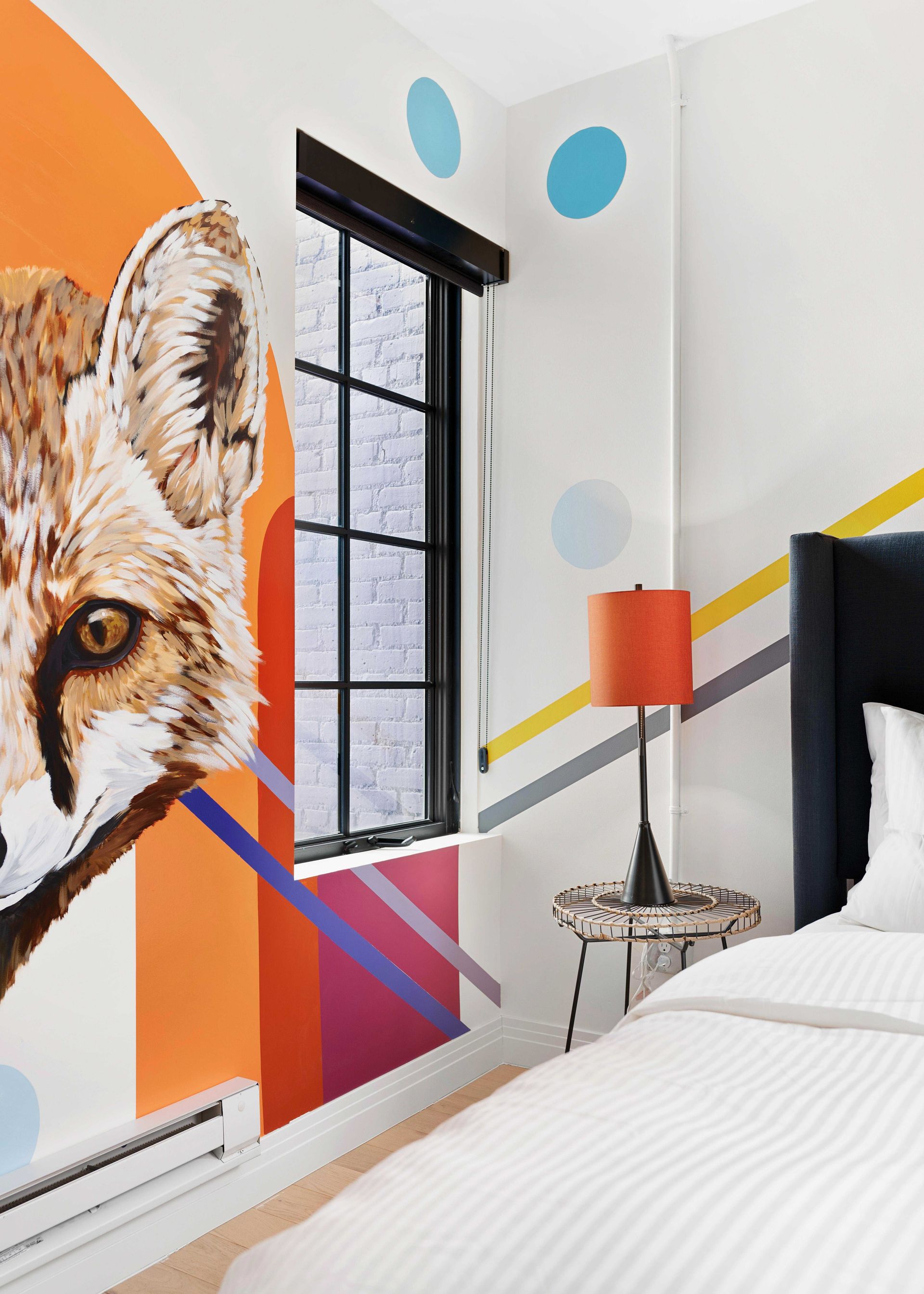 Colorful bedroom with fox mural, polka dots, window, and bed with orange lamp
