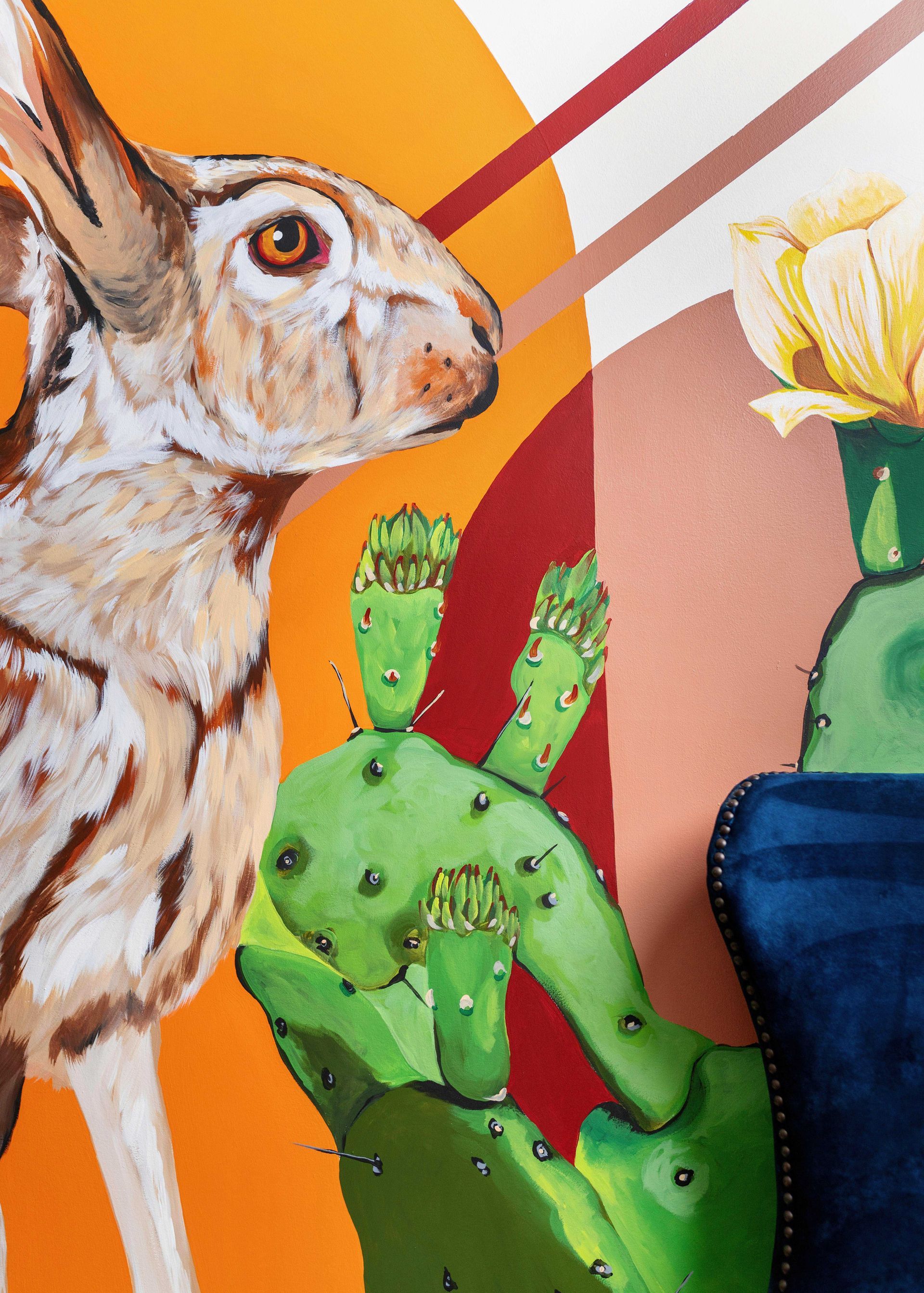 Rabbit next to green cactus sculpture with yellow flower and bold orange-red abstract background