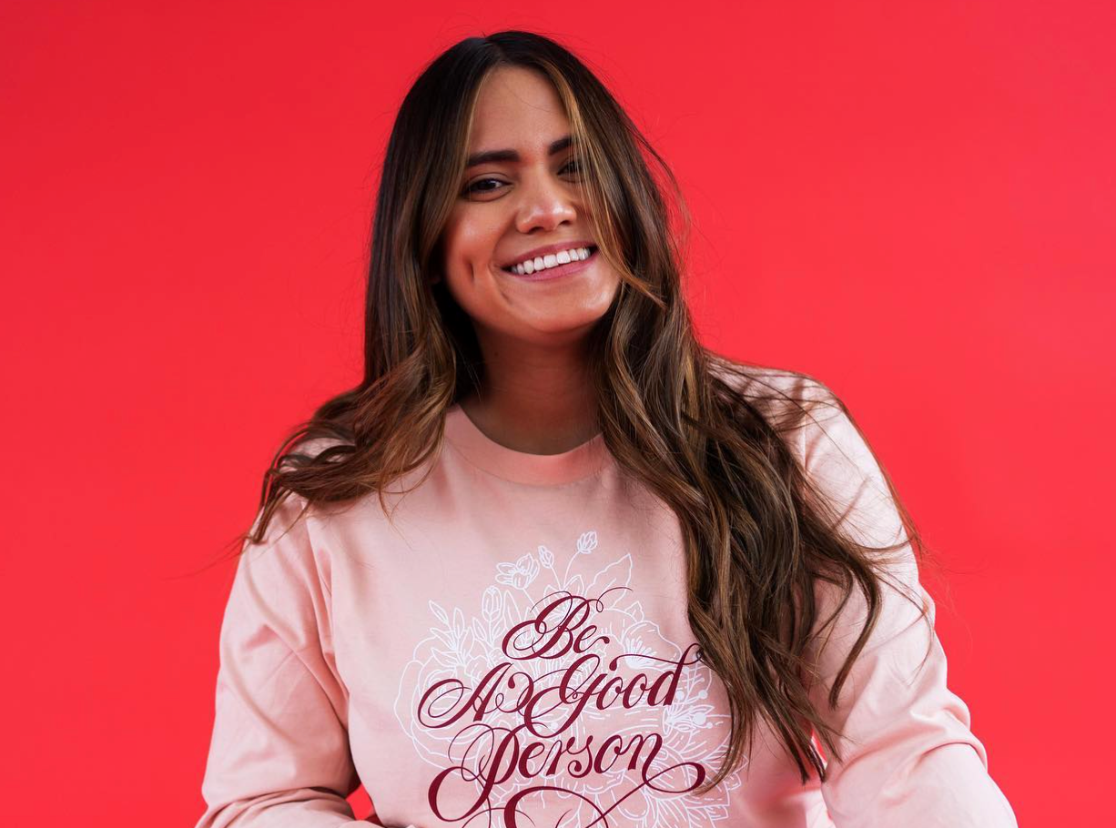 Smiling woman in a pink sweatshirt against a bright red background