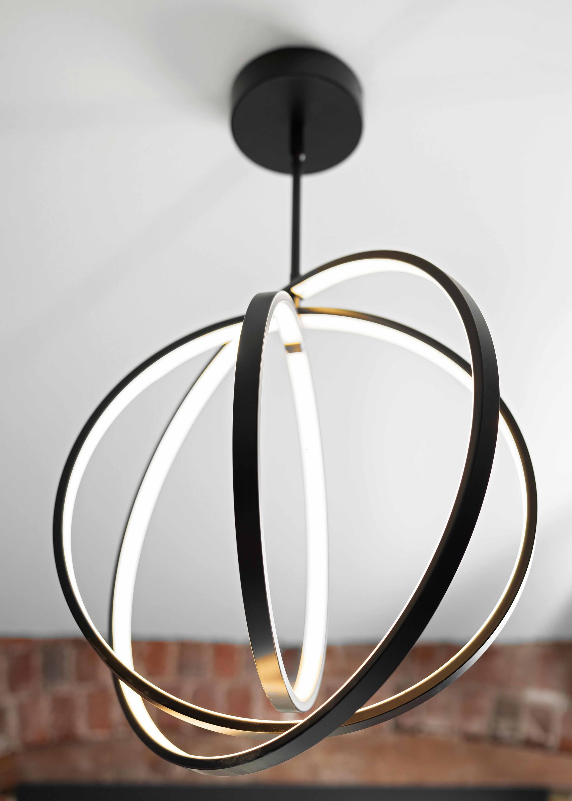 Modern pendant light with black, white, and gold circular rings hanging from the ceiling