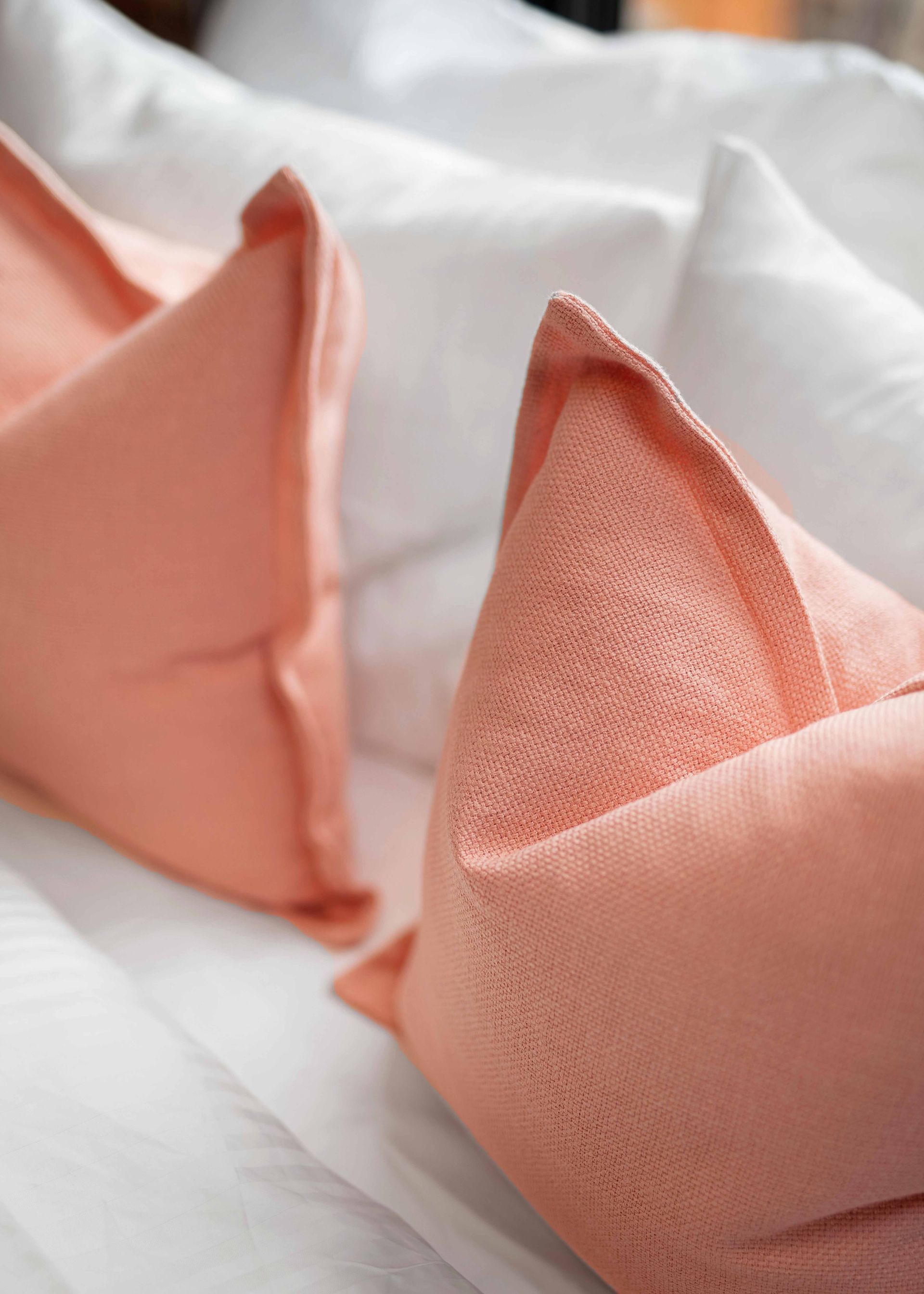 Folded peach napkins arranged on a white tablecloth, ready for a formal table setting