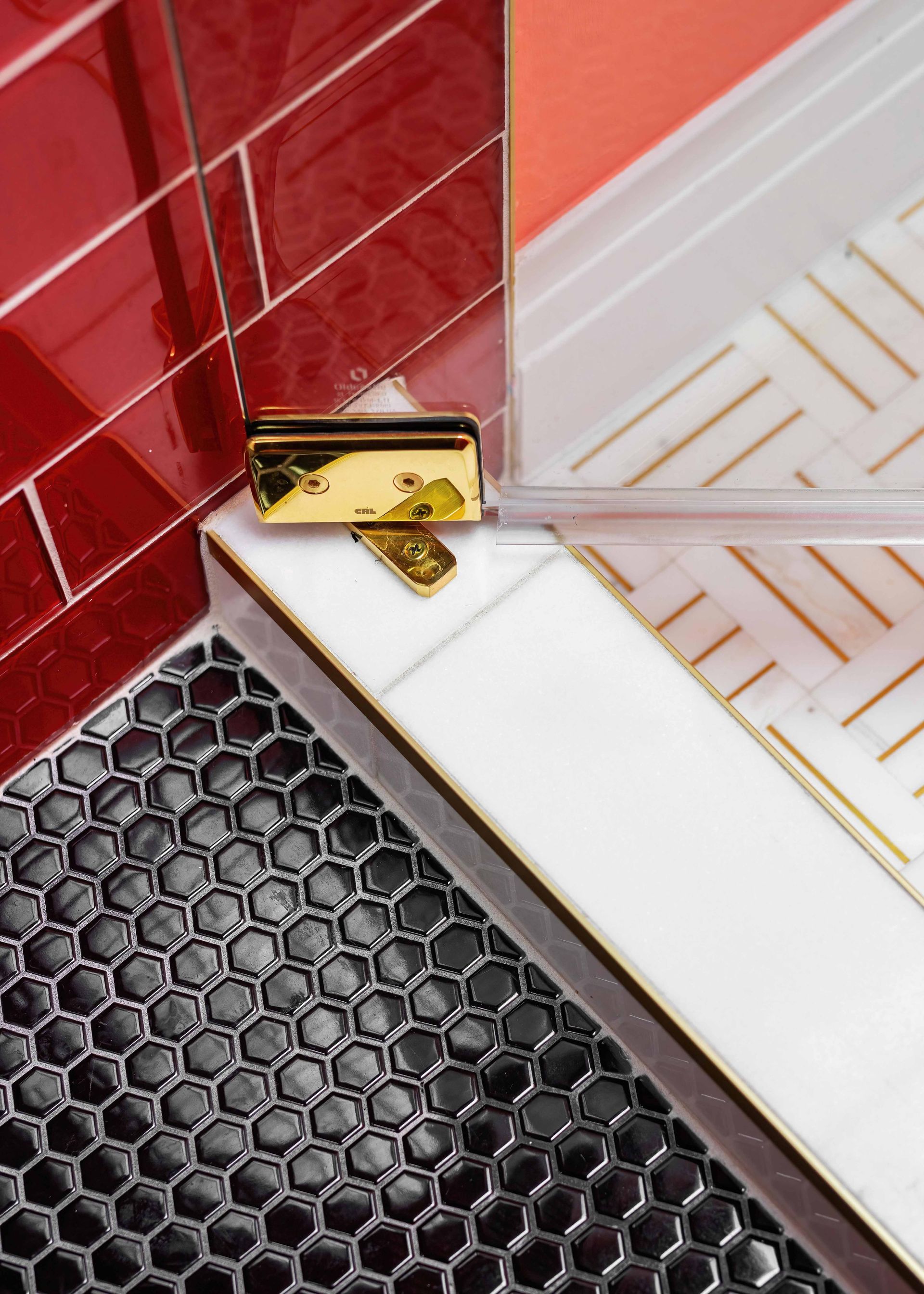 Gold hinge joining red tile, white marble, and black hexagon-pattern surfaces