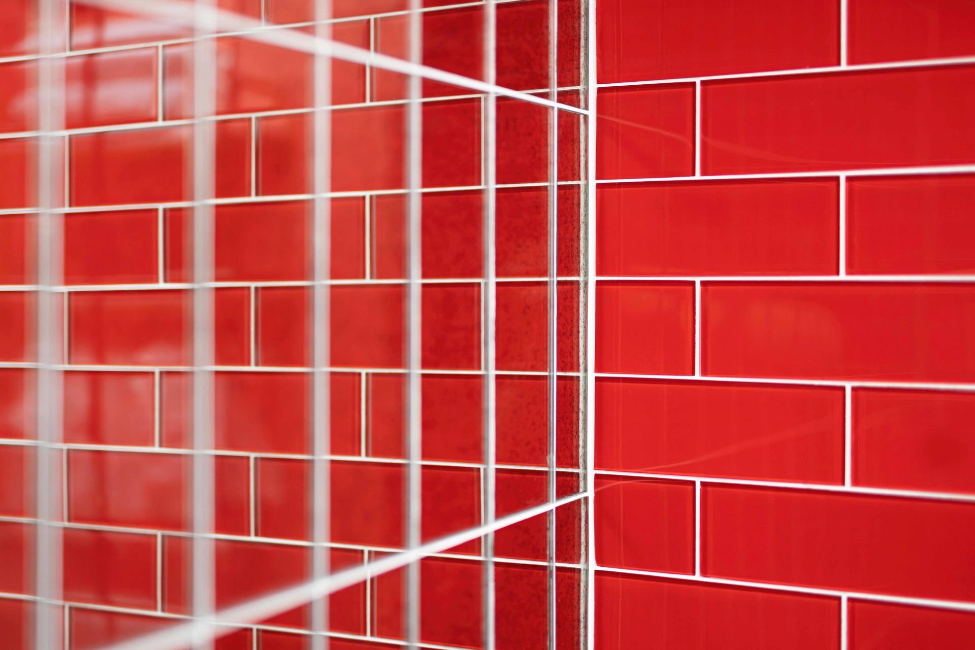 Glossy red tiled wall with white grid lines and reflections