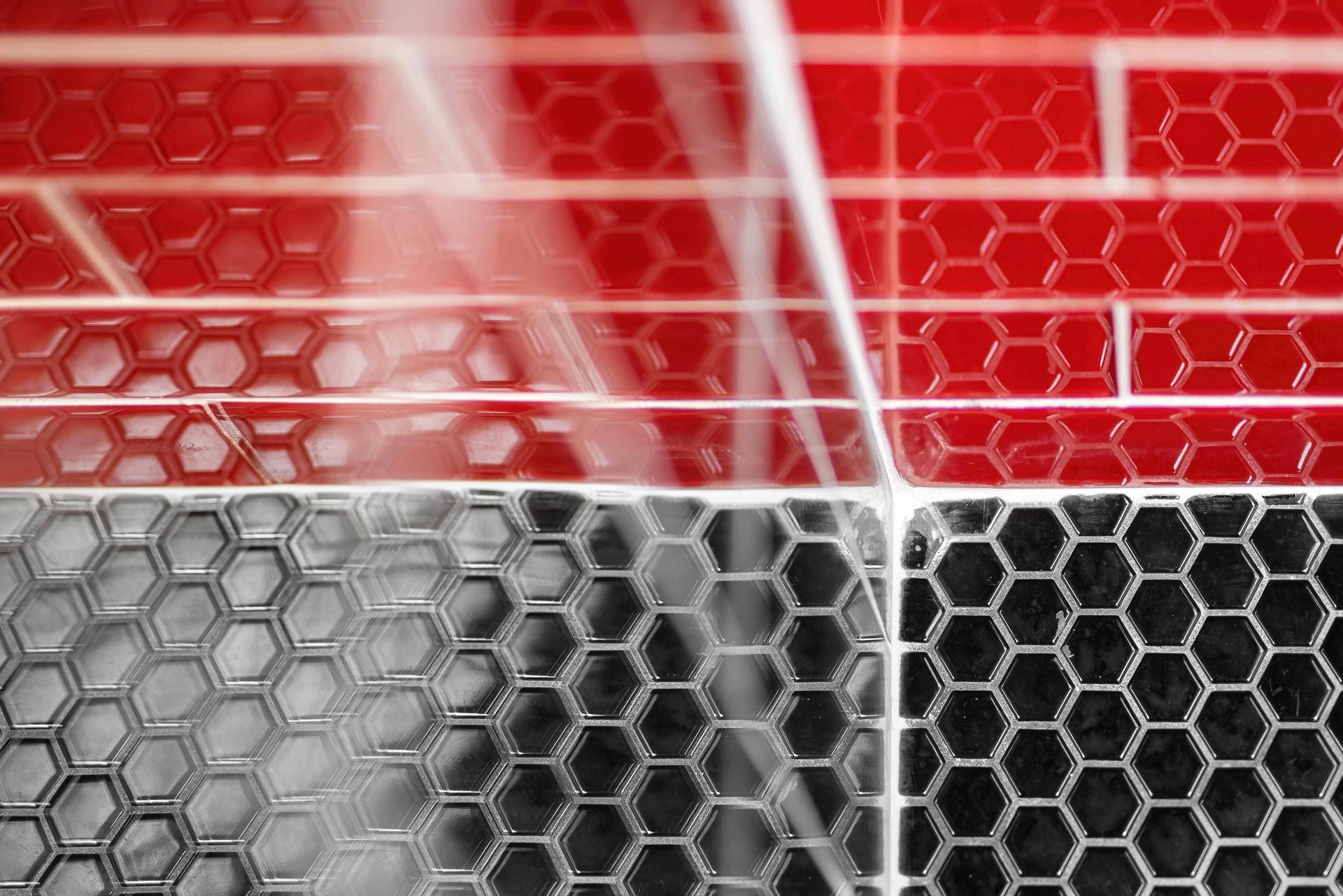 Red and gray hexagonal mesh pattern with bright white diagonal streaks