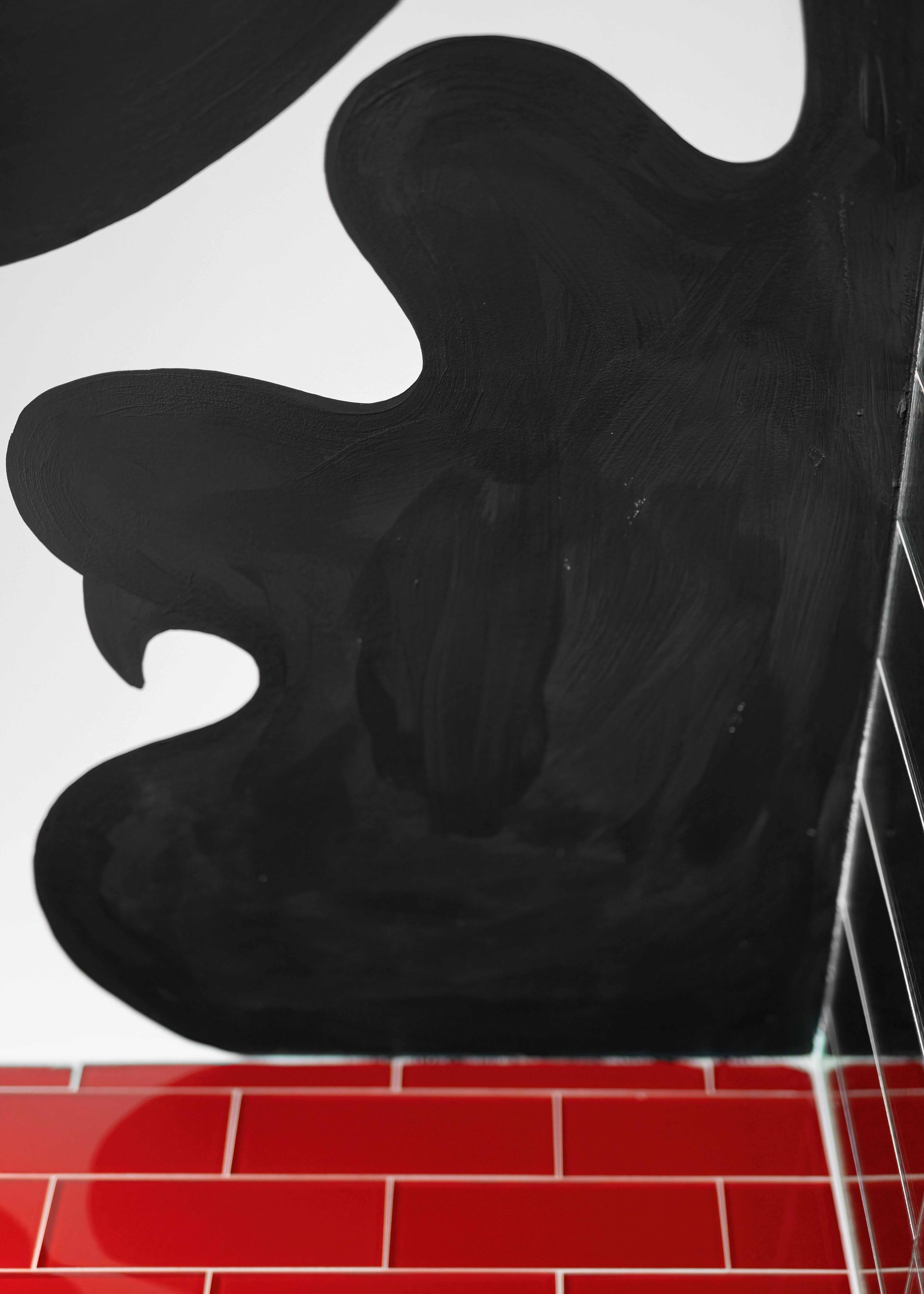 Abstract black wall art above red tiled floor with white grout lines