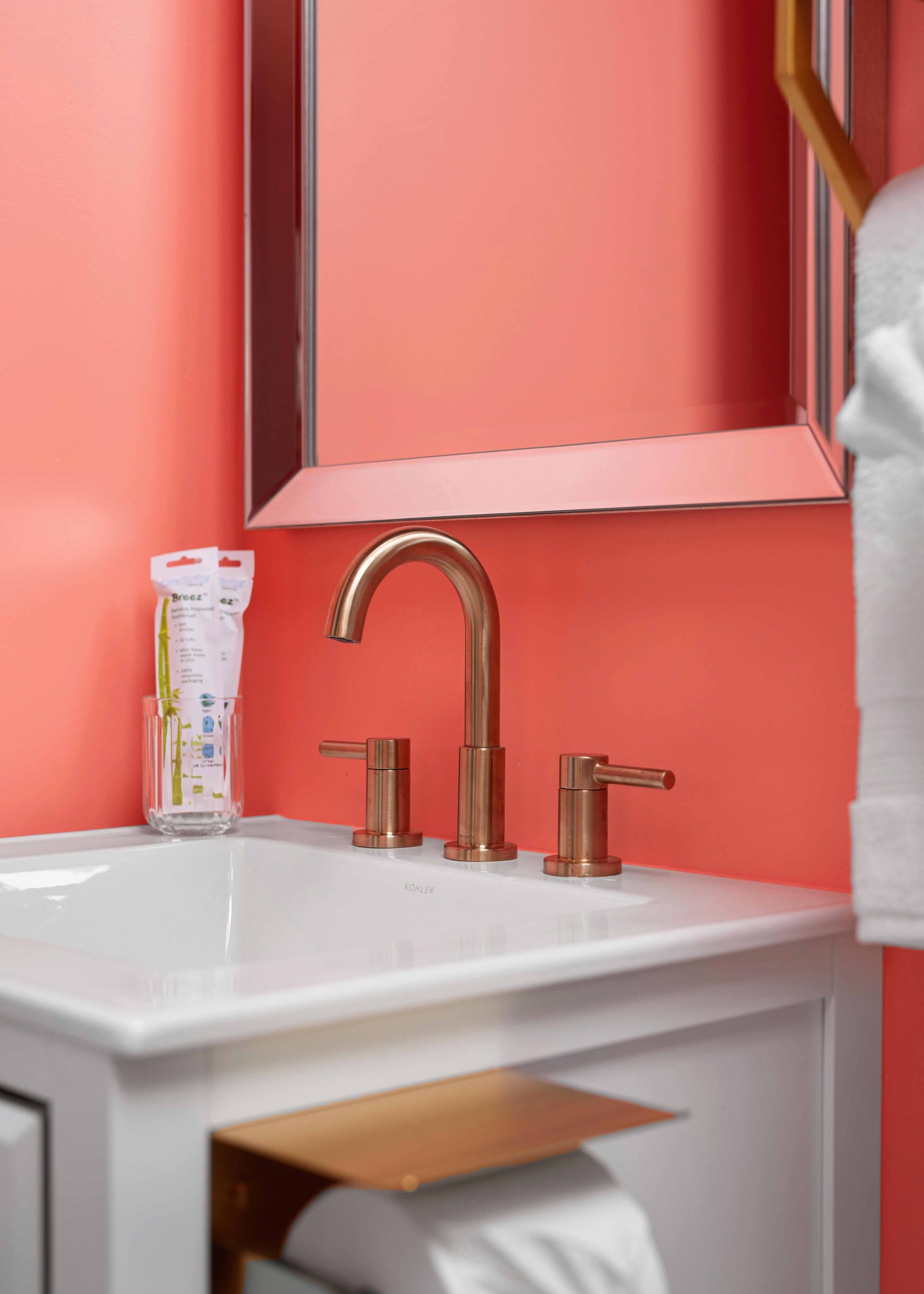 Pink bathroom sink with gold faucet and mirror above it