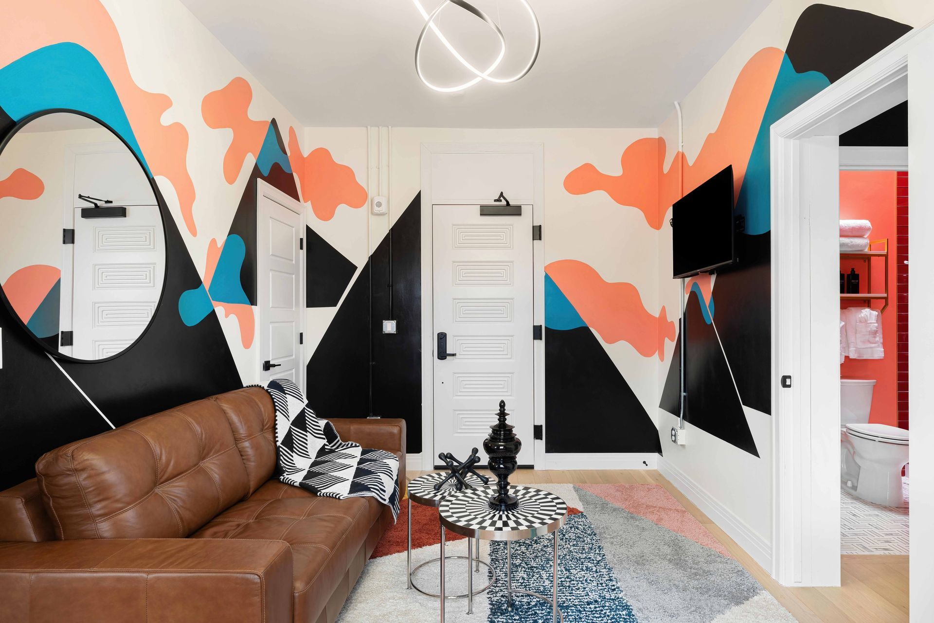 Colorful living room with mural walls, brown sofa, patterned rug, and white doorways