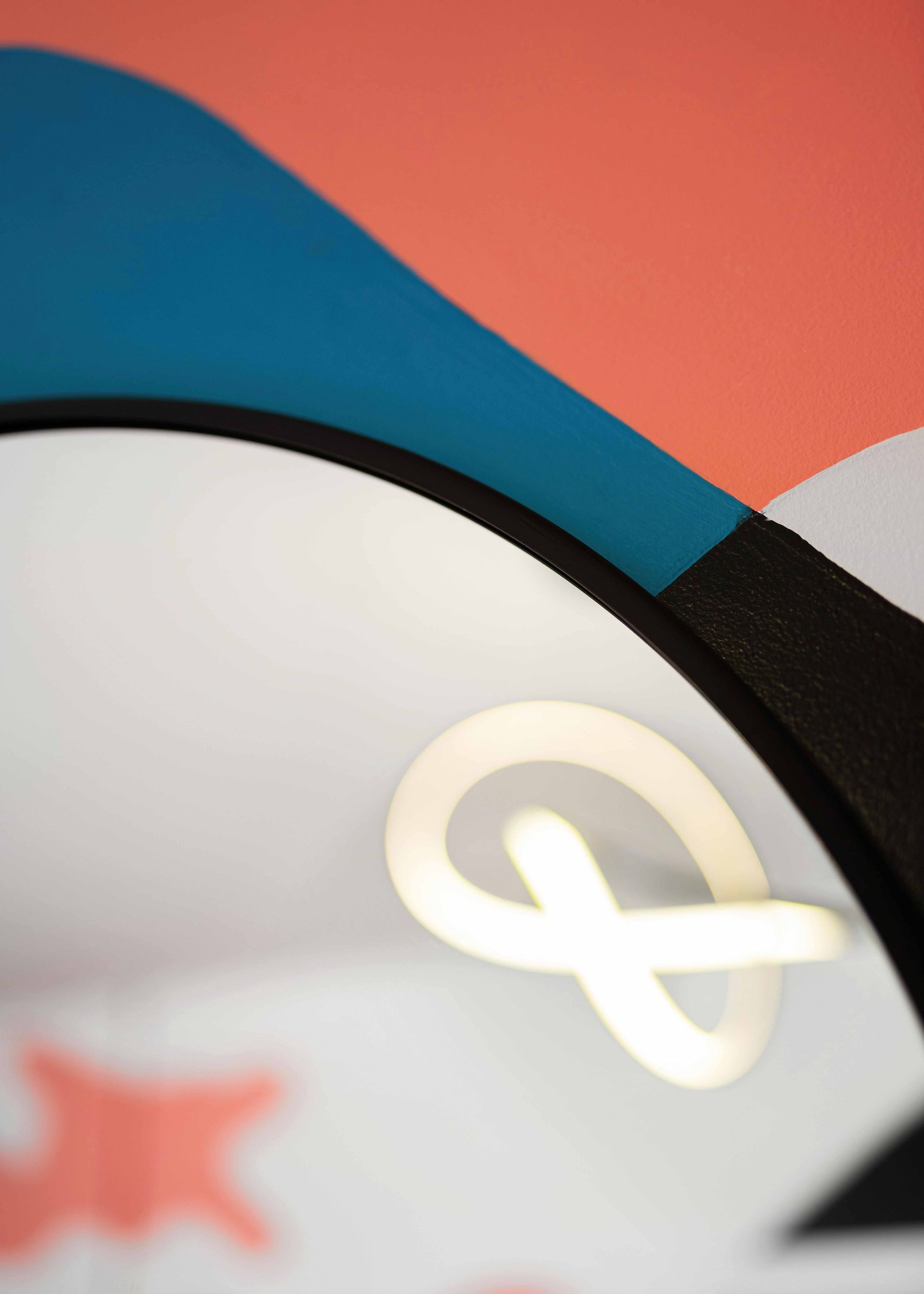 Close-up of a colorful abstract graphic with blue, red, white, and black curved shapes and a glowing symbol.