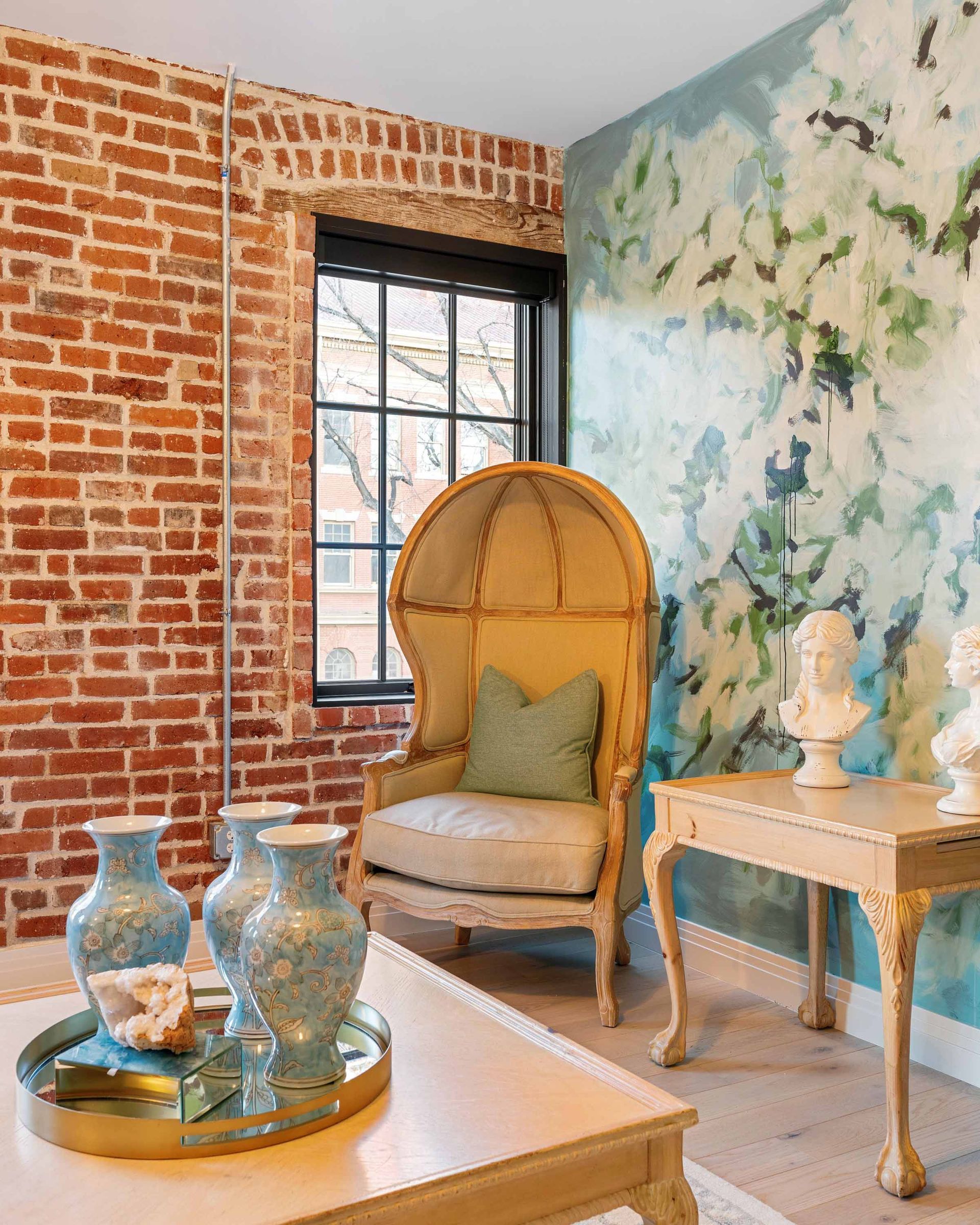 Elegant room with exposed brick, floral wallpaper, wicker chair, and glass vases on a round table