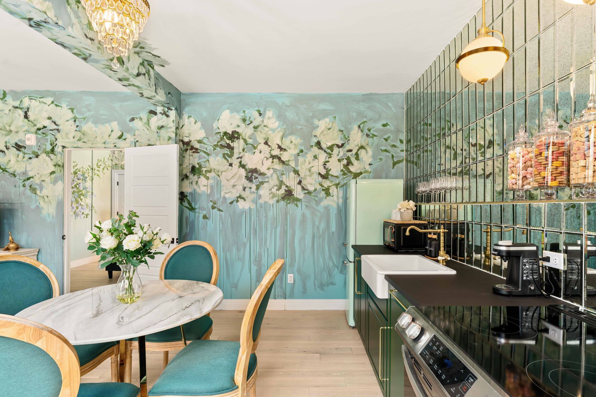 Floral-themed café with teal chairs, round marble tables, and a bar counter with hanging lights