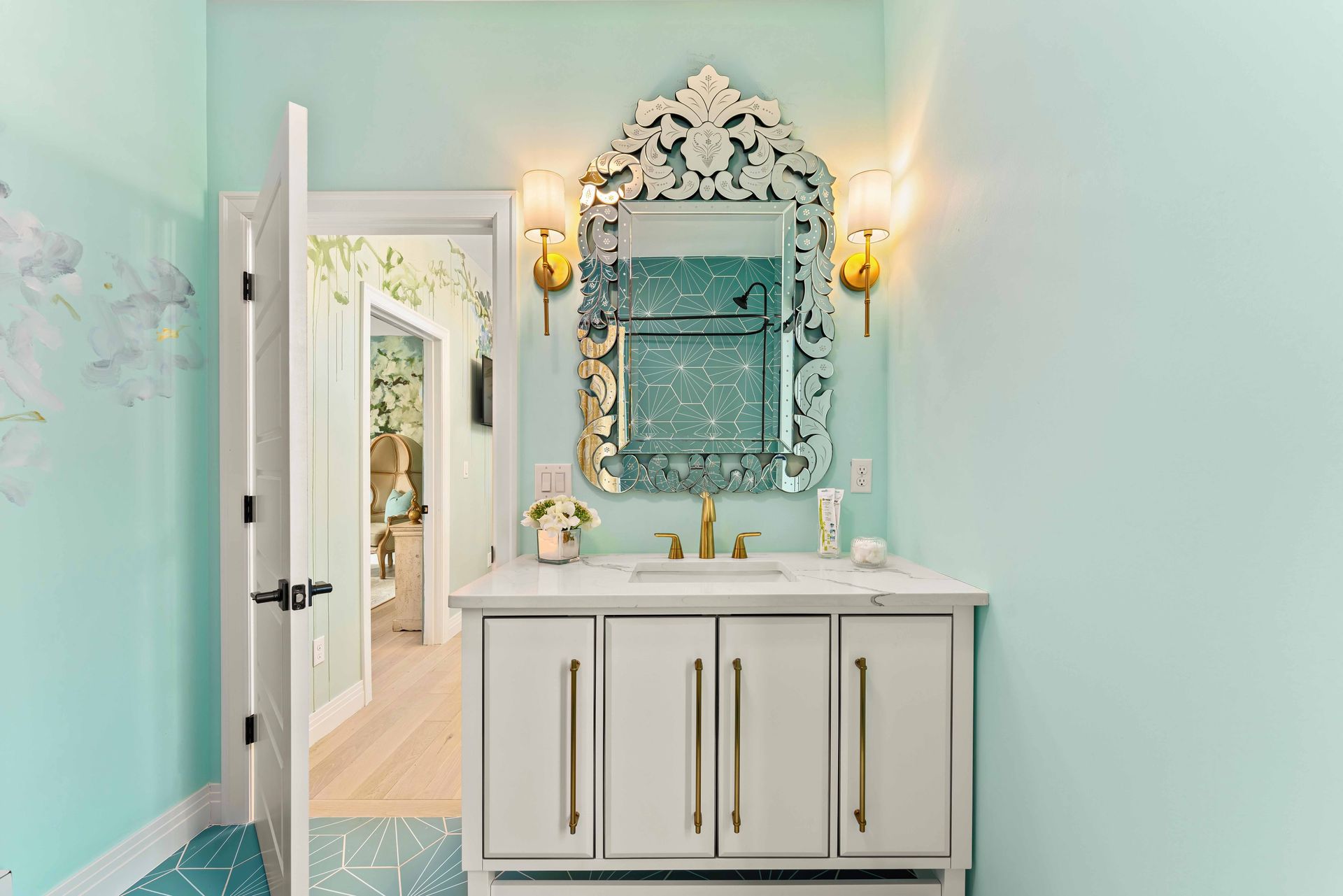 Mint bathroom with ornate mirror, white vanity, and gold wall sconces