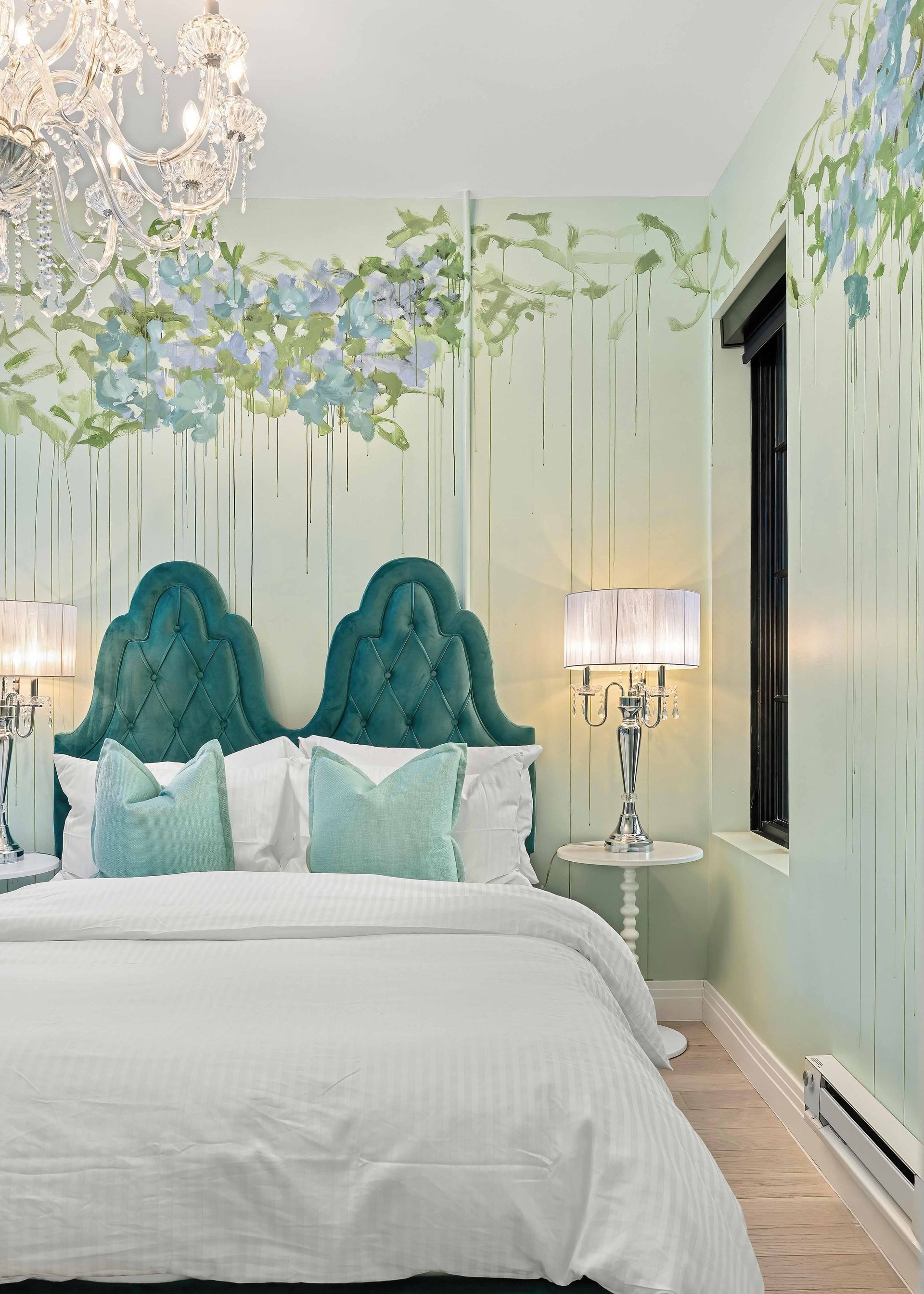 Elegant bedroom with teal tufted headboards, floral wall mural, and white bedding