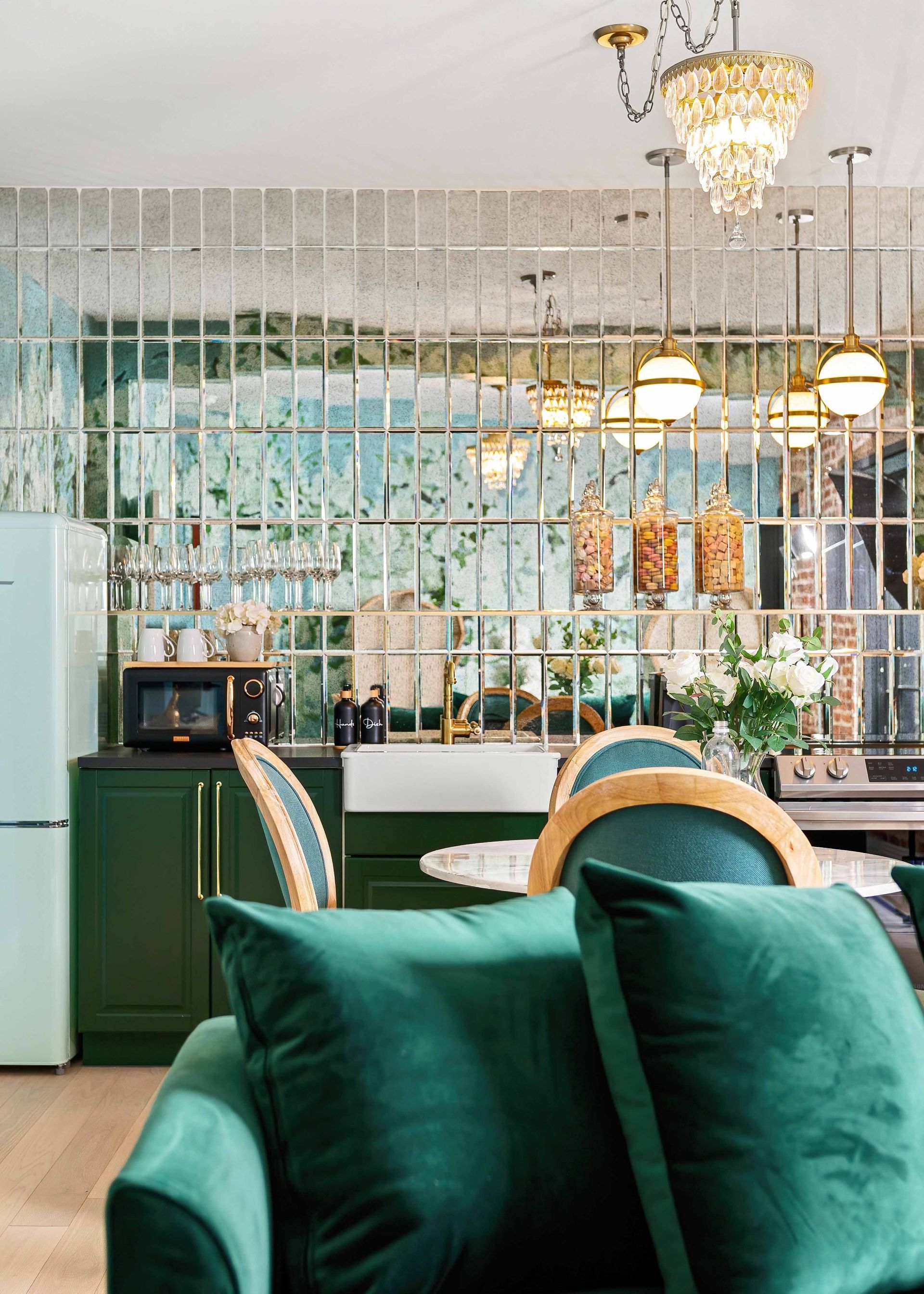 Elegant café interior with green sofa, mirrored wall, hanging lights, and mint refrigerator