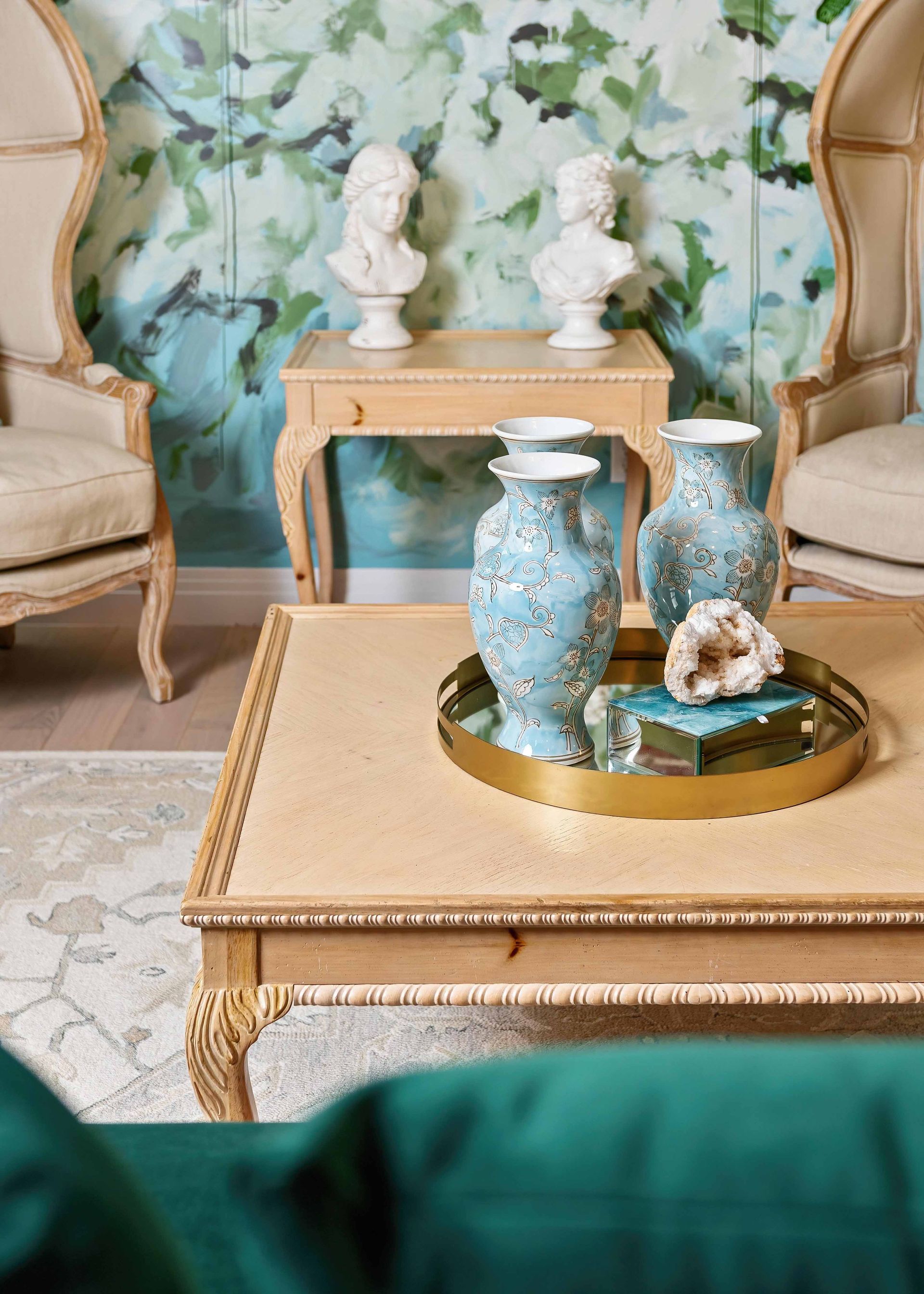 Elegant living room with blue patterned vases on a gold tray atop a carved coffee table