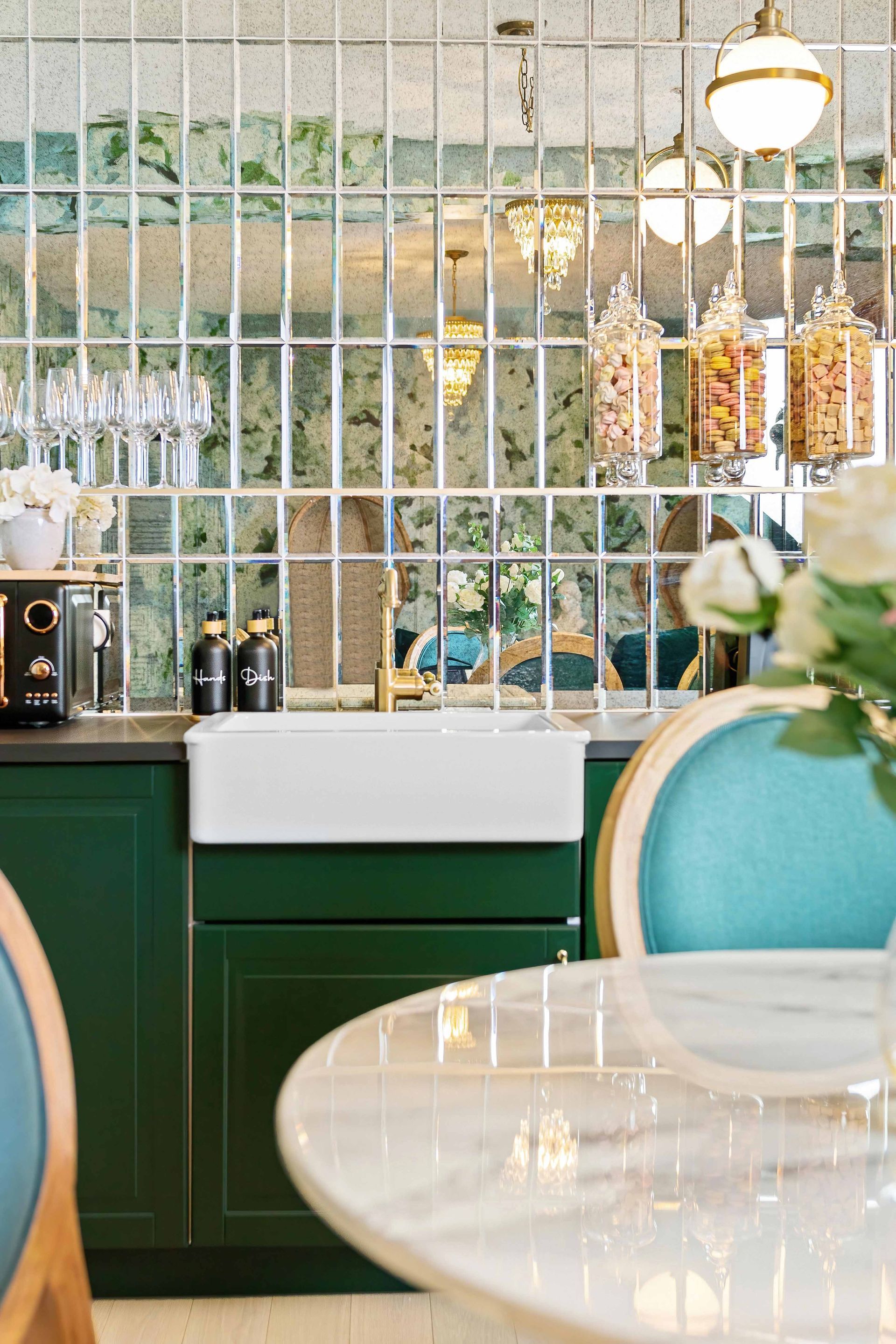 Elegant café counter with green cabinetry, white tiled wall, hanging lights, and teal chairs