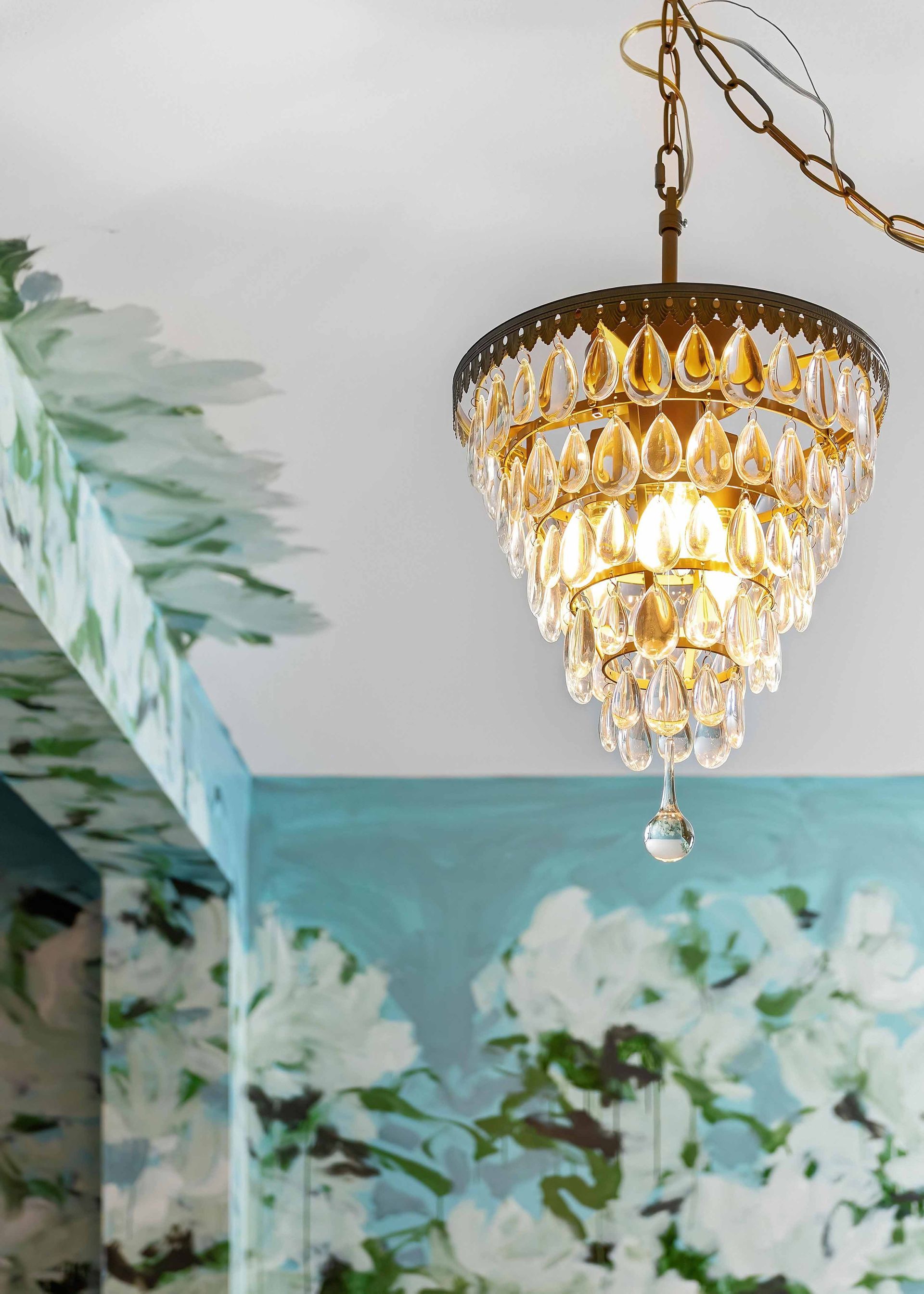 Crystal chandelier hanging in a room with floral wall art and a white ceiling