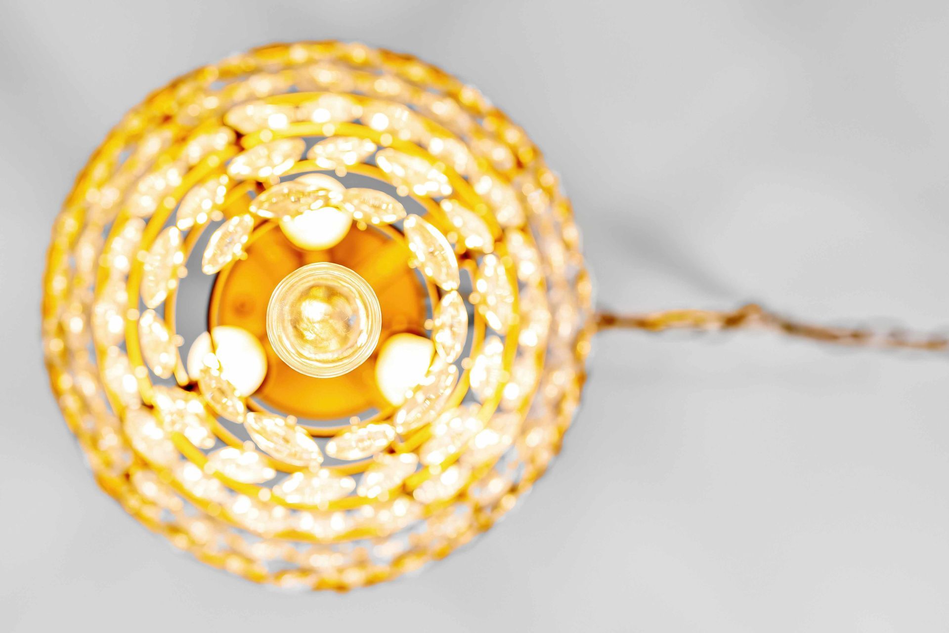 Top-down view of a glowing gold spiral woven pendant light on a white background