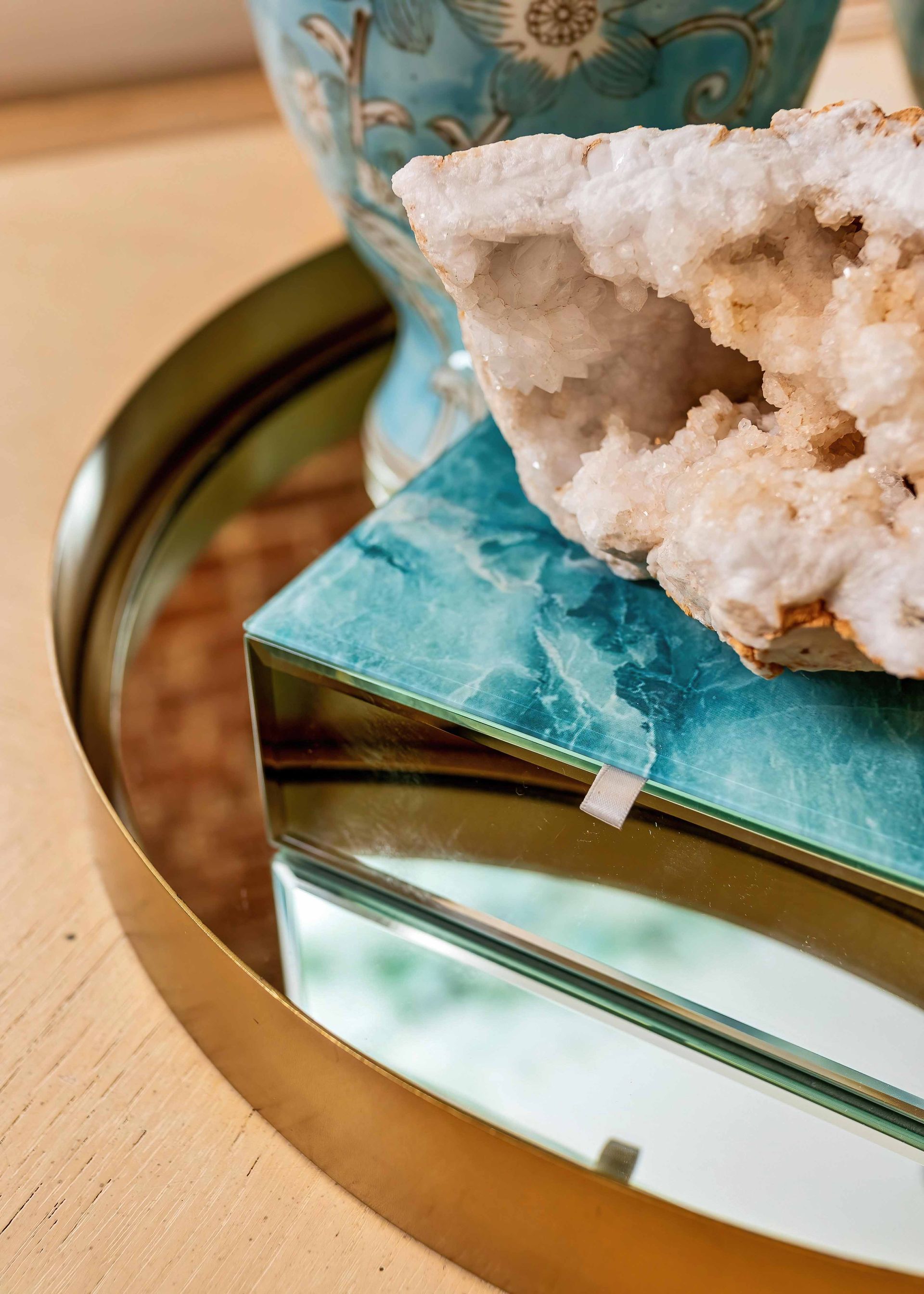 Turquoise geode decor atop a mirrored gold tray on a wooden surface
