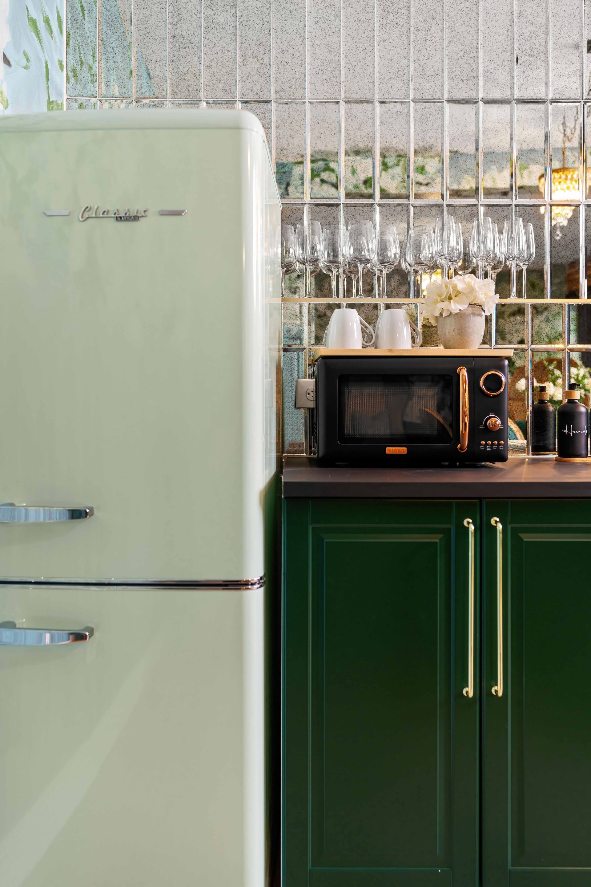 Mint fridge beside green cabinets with a microwave in a bright kitchen