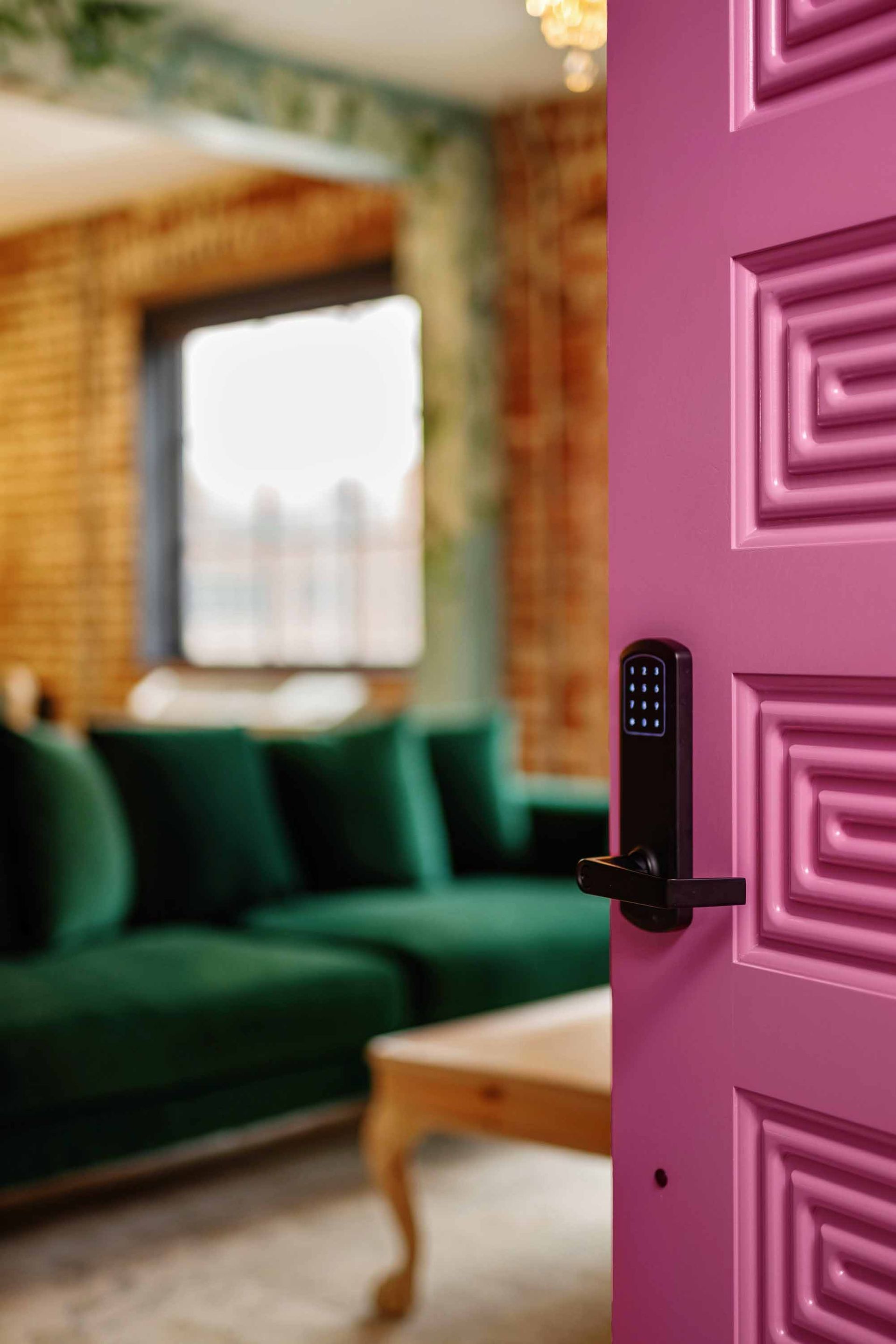 Open magenta door revealing a green sofa in a softly lit living room