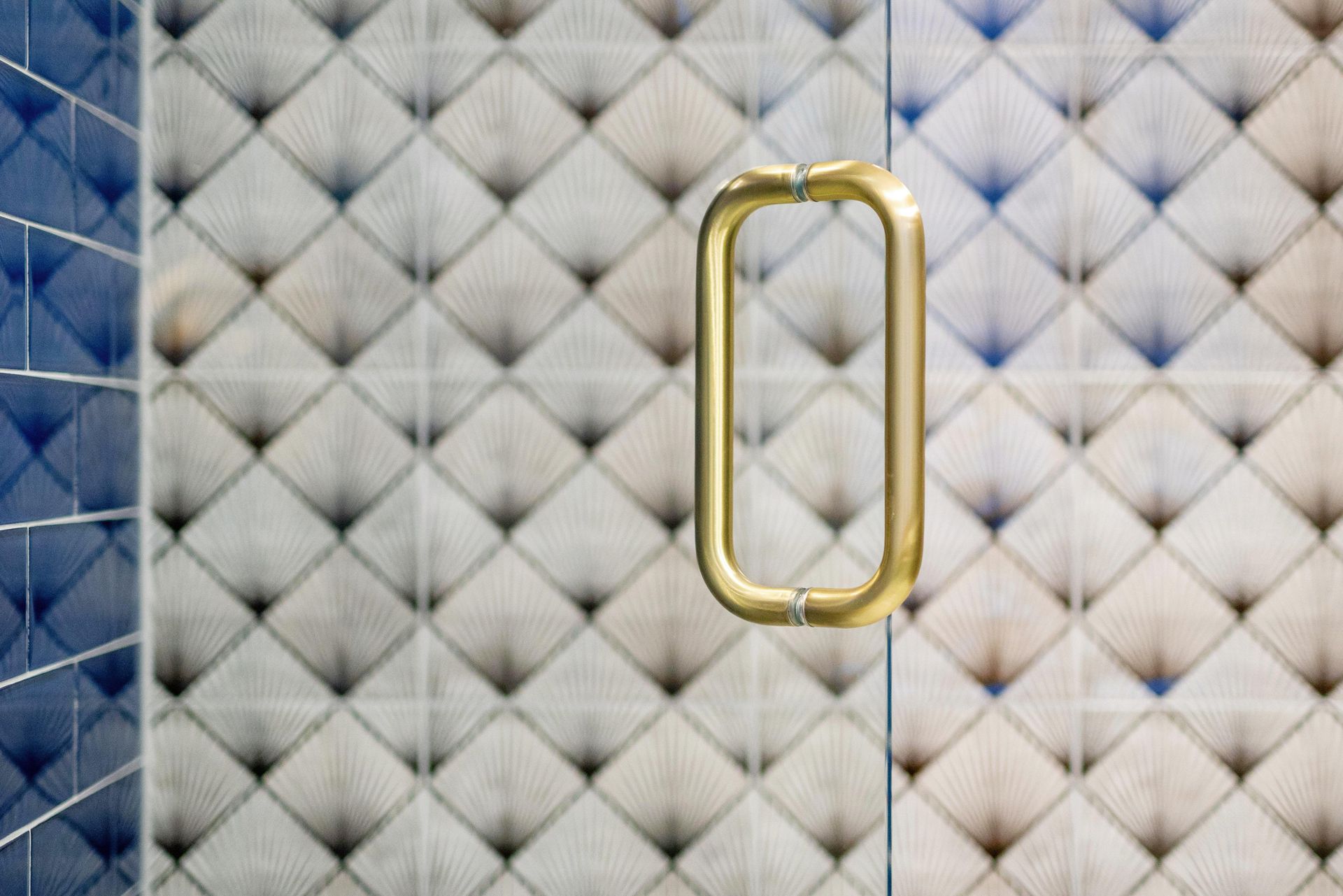 Gold door handle on a quilted gray metal surface.