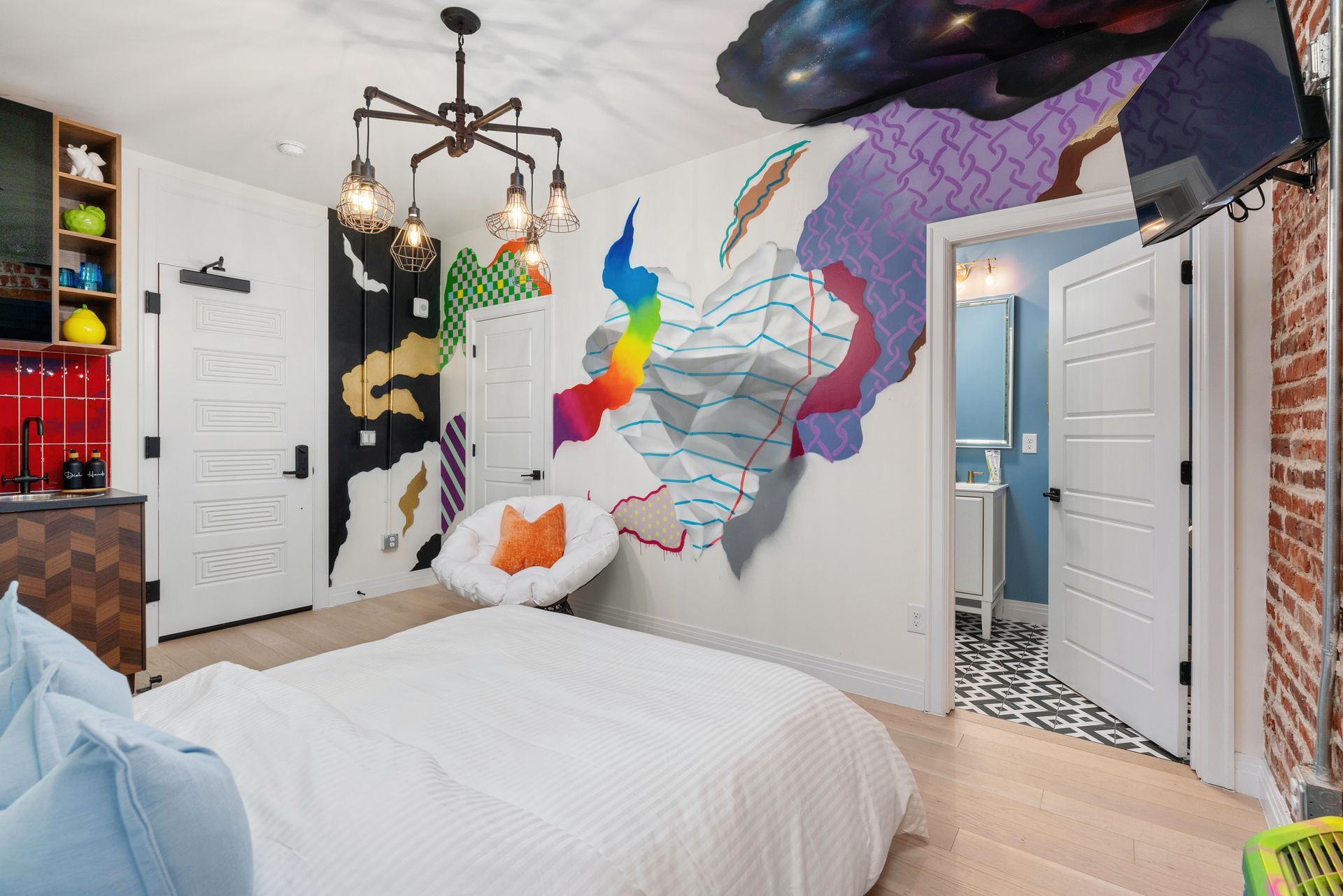 Colorful bedroom with mural wall, white bed, open doors, and hanging light fixture