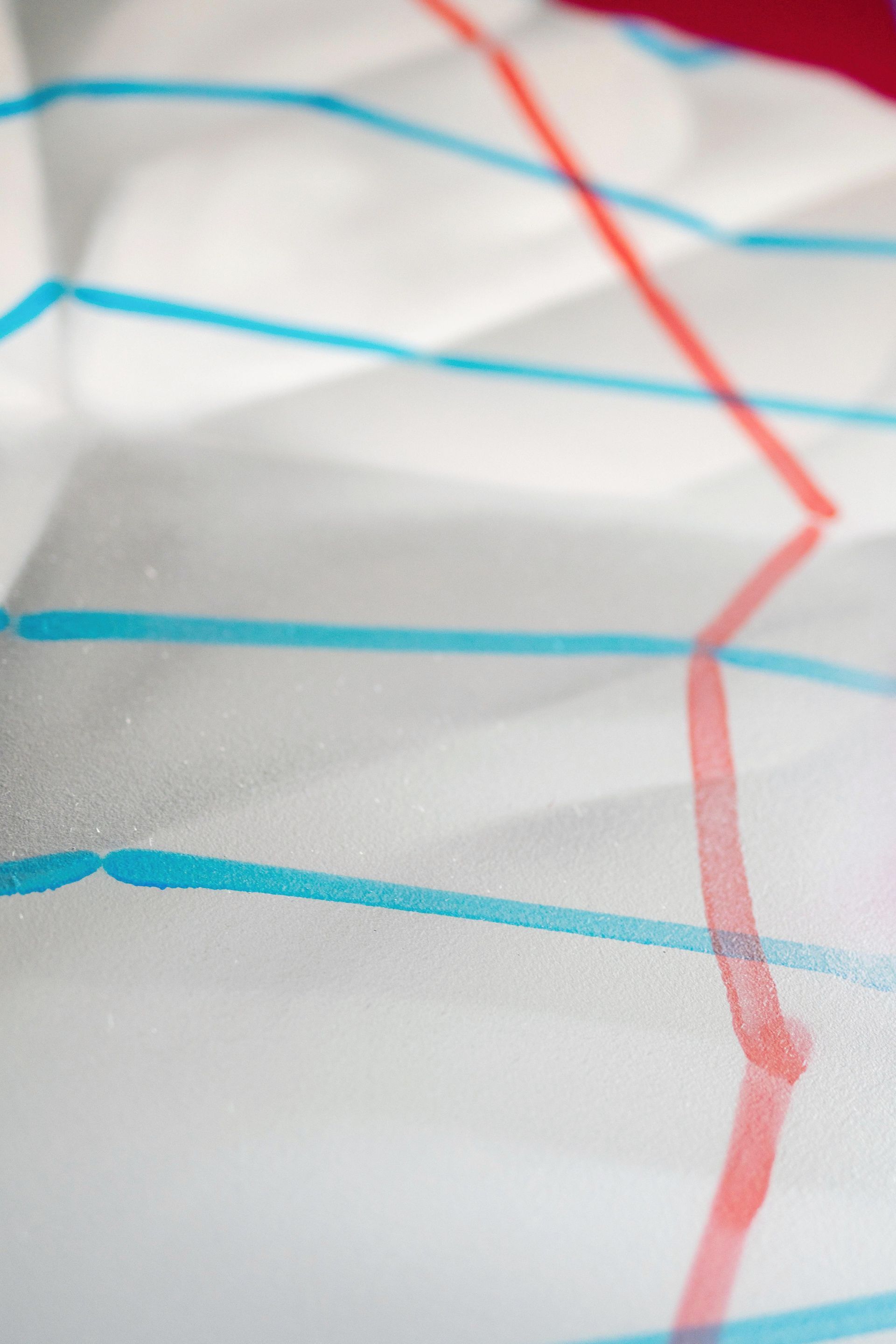 Close-up of white fabric with blue horizontal stripes and a red vertical line pattern