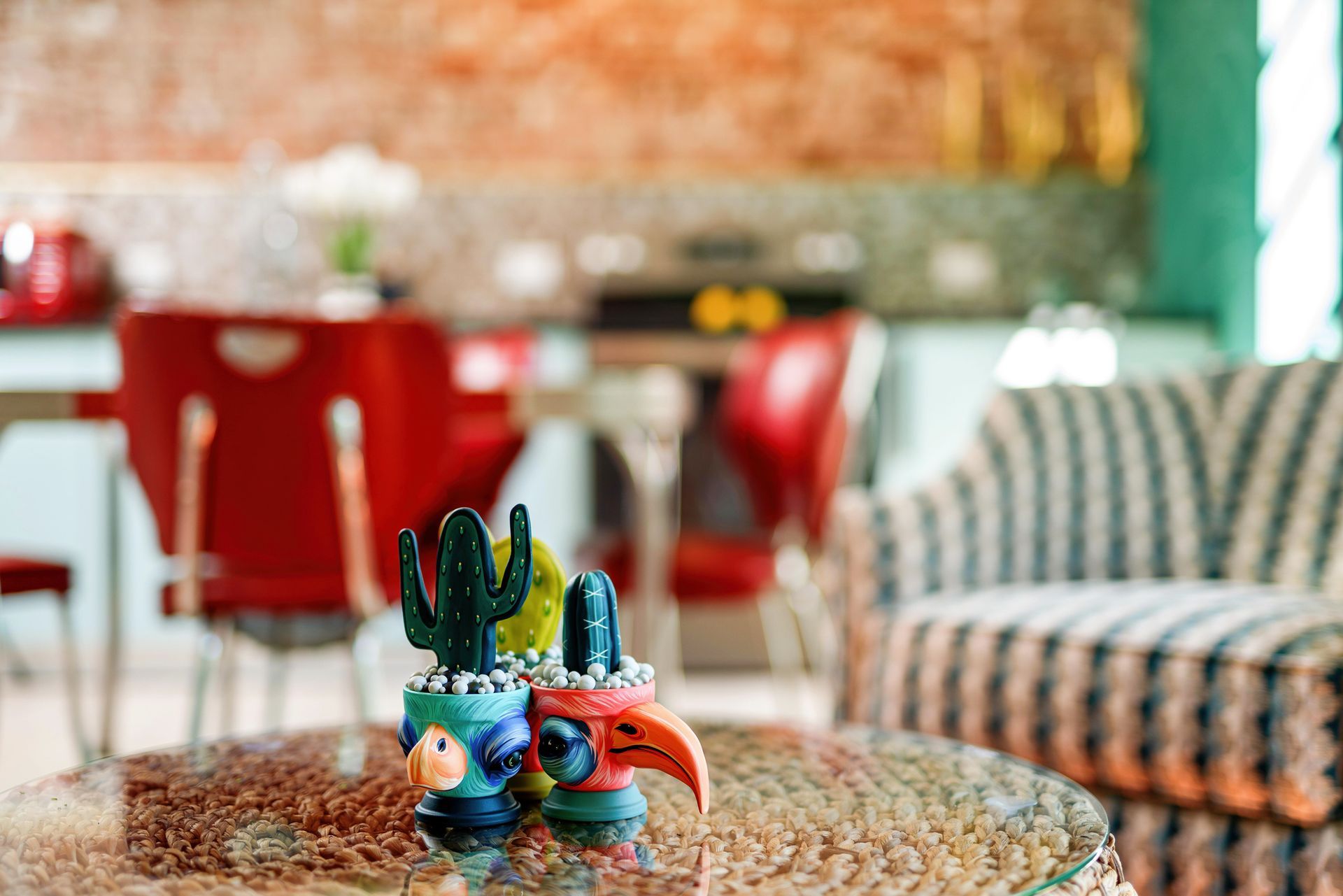 Colorful ceramic figurines on a table in a cozy cafe with red chairs and patterned seating
