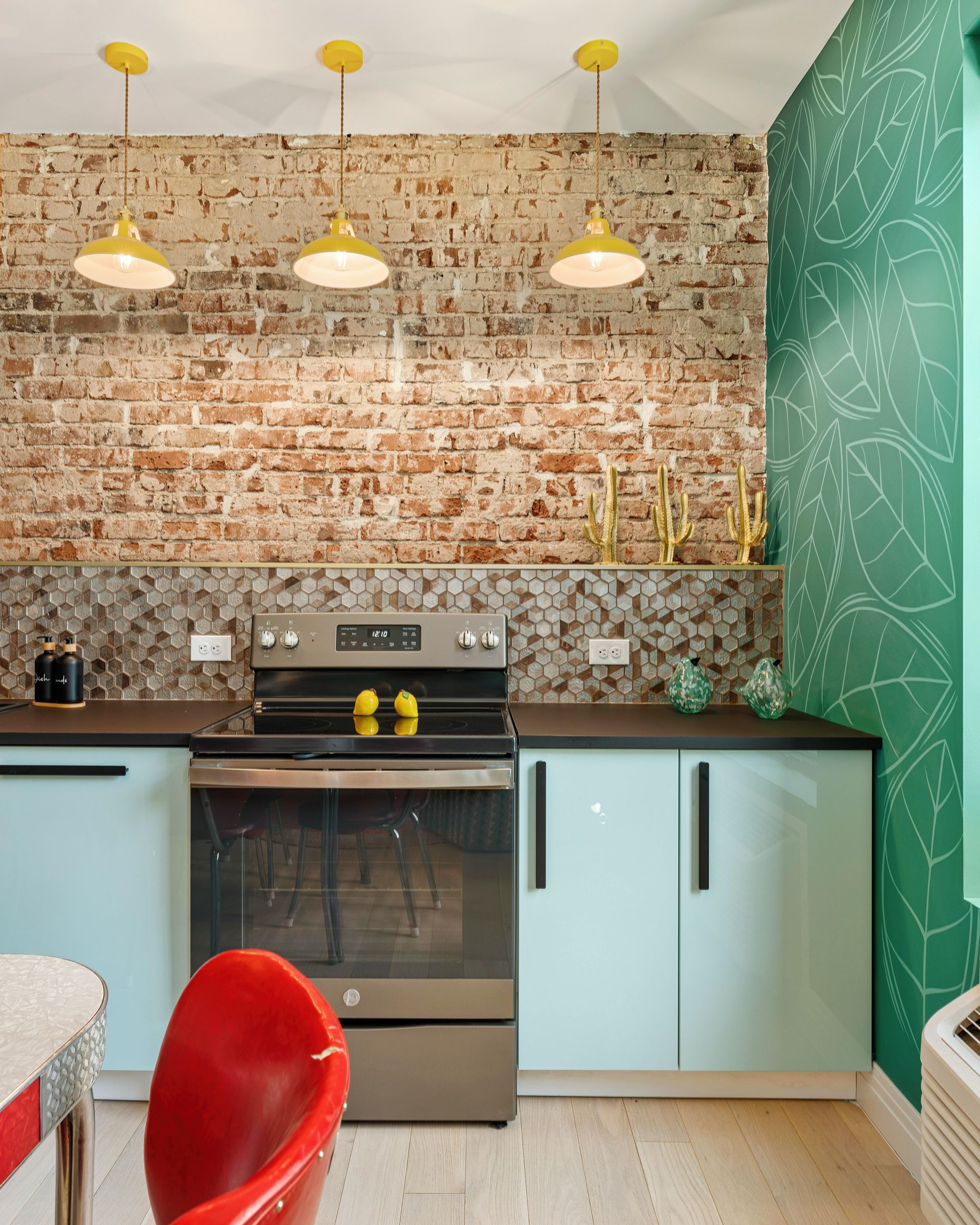 Modern kitchen with light blue cabinets, brick backsplash, yellow pendant lights, and a green chalkboard wall