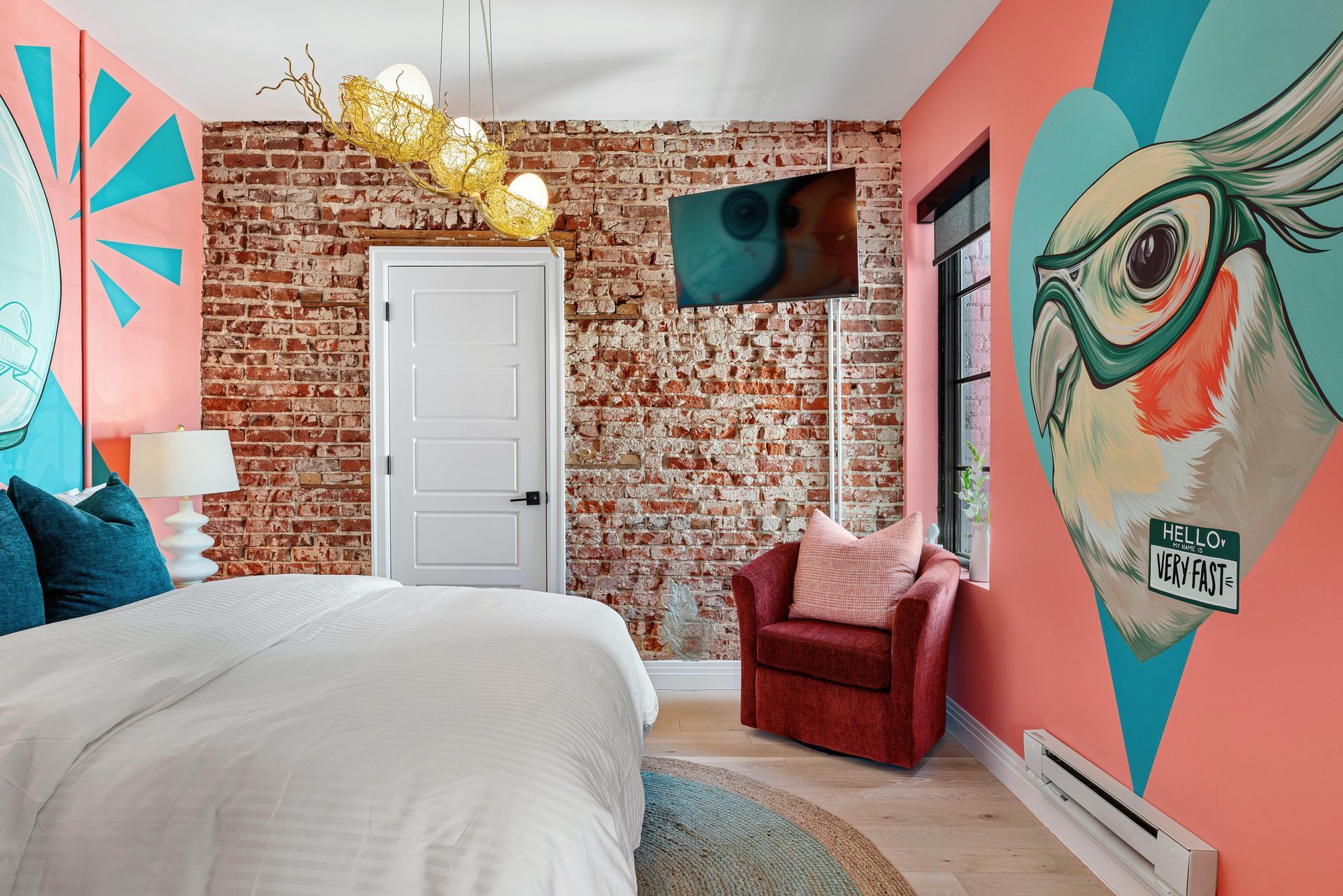 Colorful bedroom with pink walls, mural art, a brick accent wall, and a white bed with teal pillows