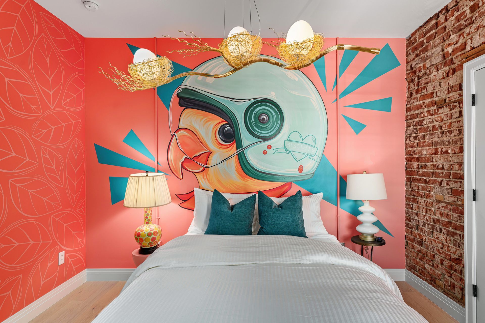 Colorful bedroom with bold coral walls, tropical mural headboard, and twin bedside lamps.