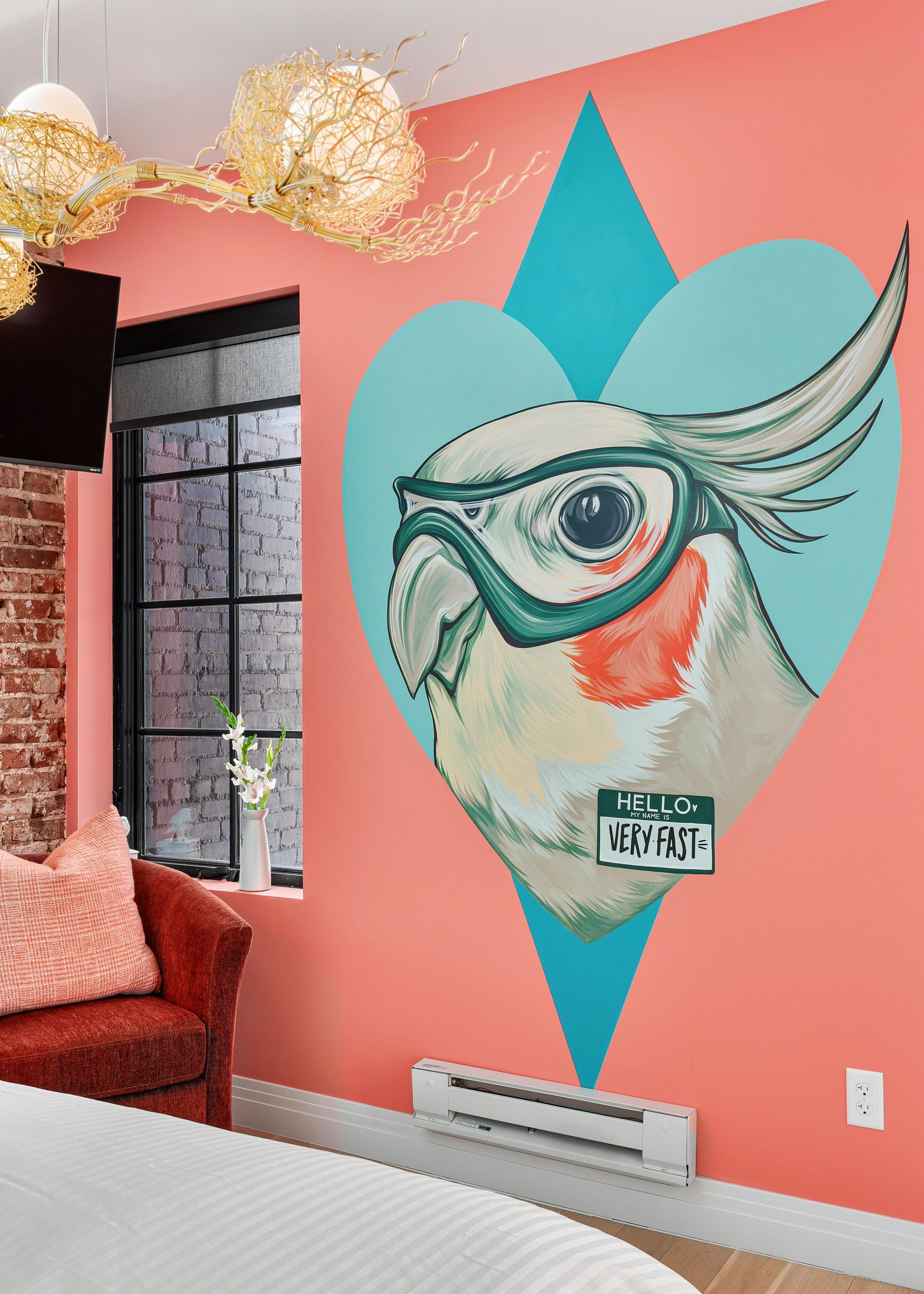 Coral room wall with a turquoise diamond mural featuring a stylized bird face and eye