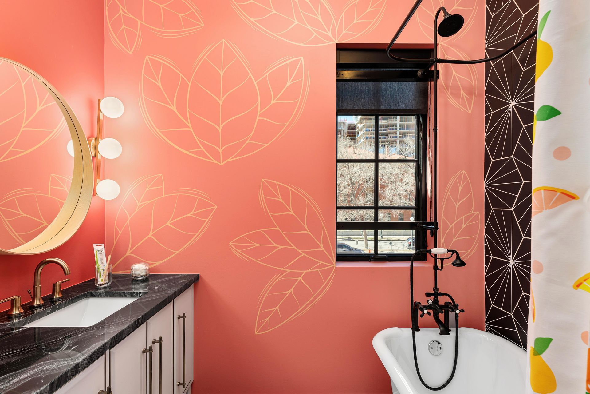 Pink bathroom with floral wall art, black vanity, window, and freestanding tub