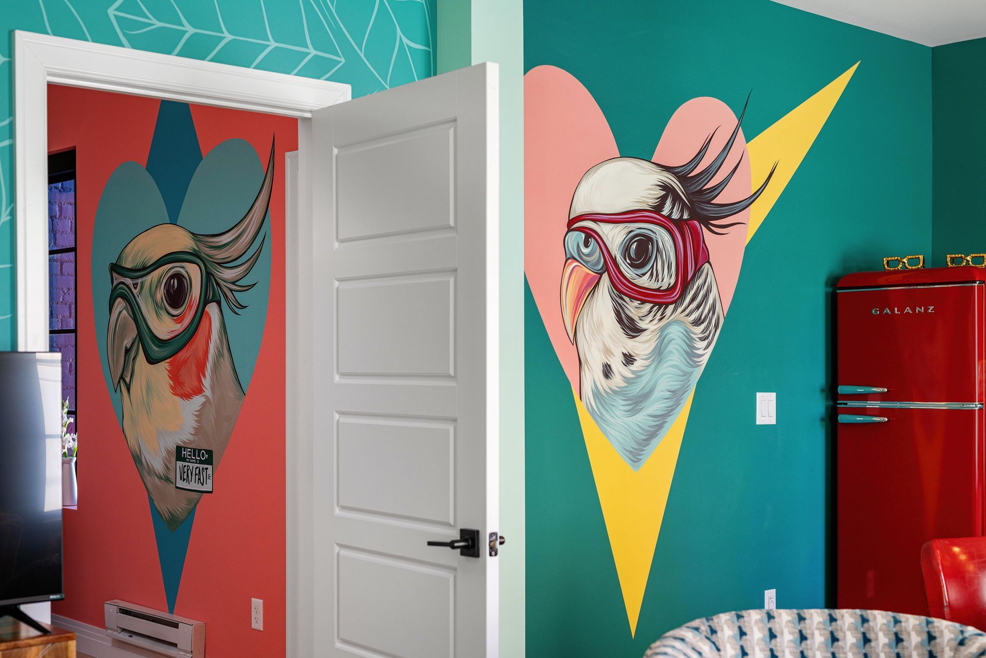 Colorful room with teal walls, large cow murals, white door, and red refrigerator.