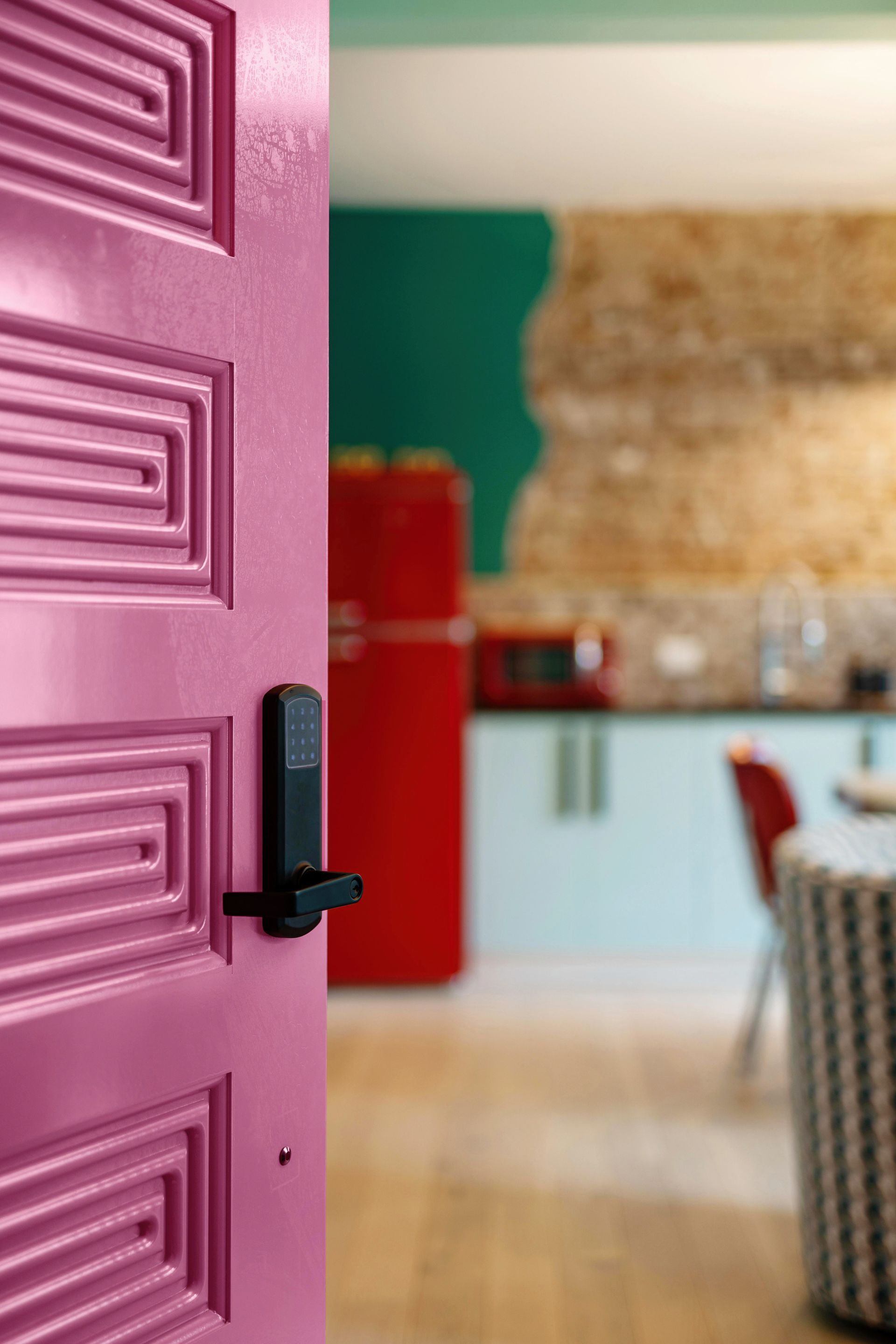 Open pink door into a bright kitchen with a red fridge and green wall