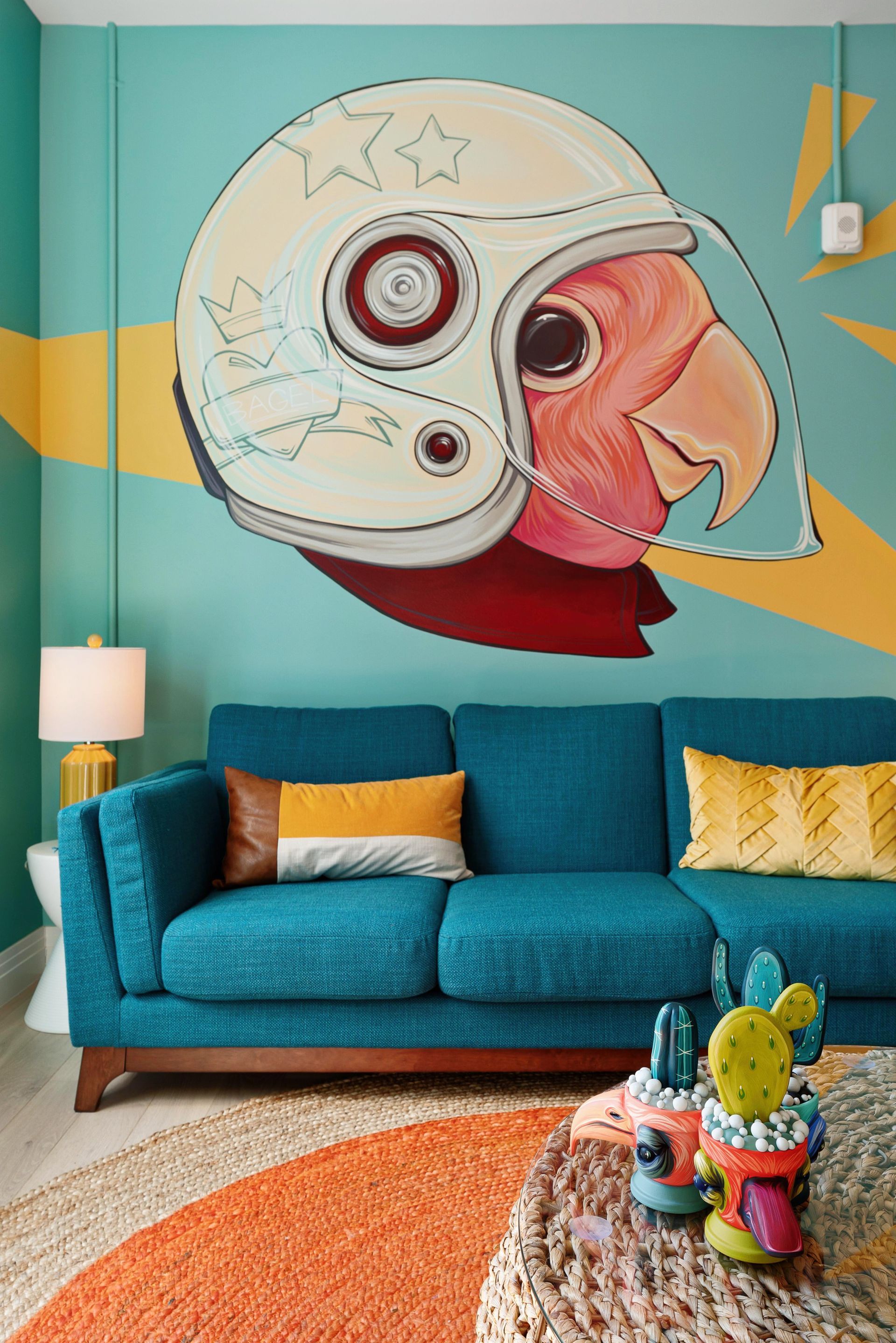 Colorful living room with teal sofa beneath a large mural of a helmeted face on a turquoise wall