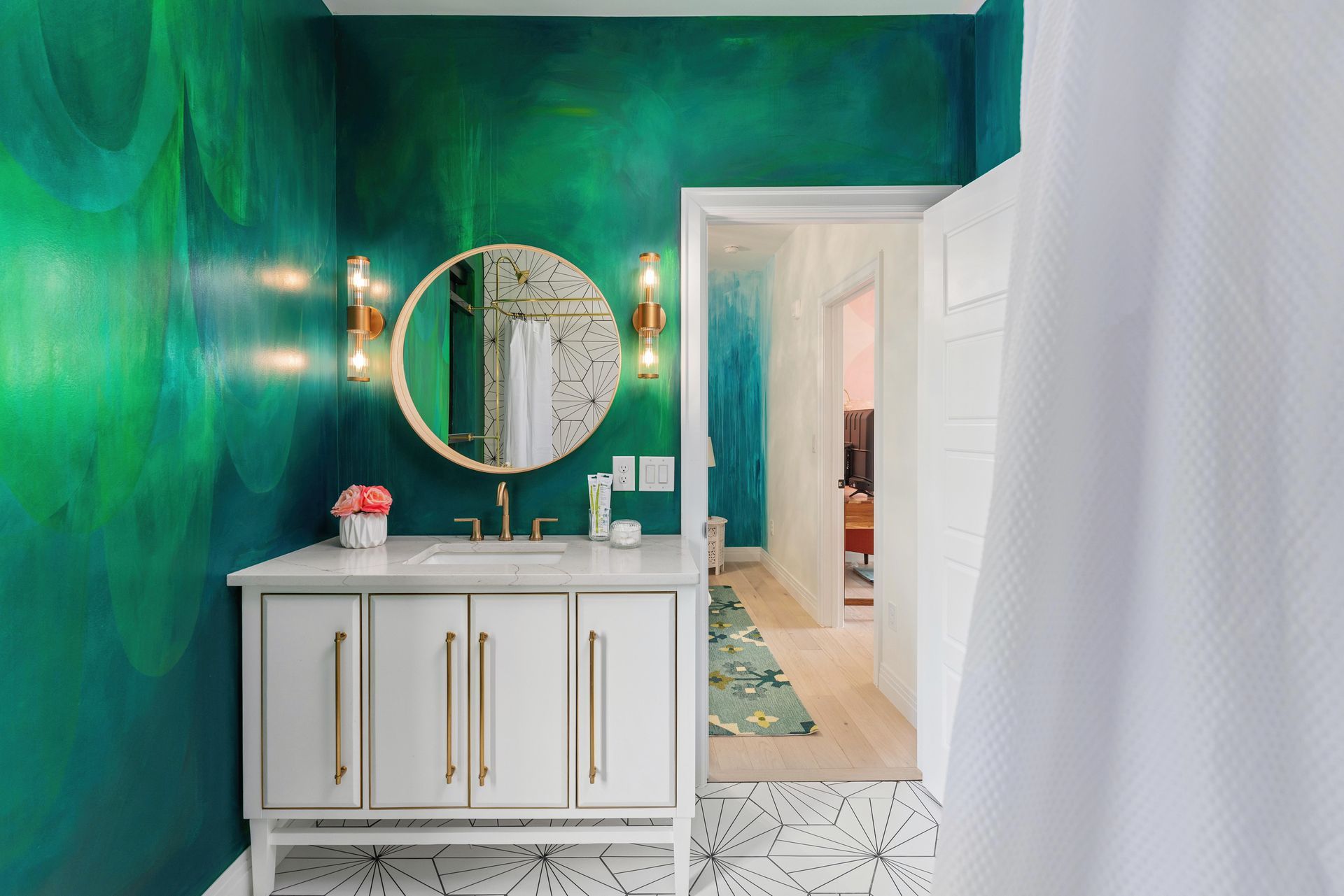 Teal bathroom with gold mirror, white vanity, and patterned tile floor